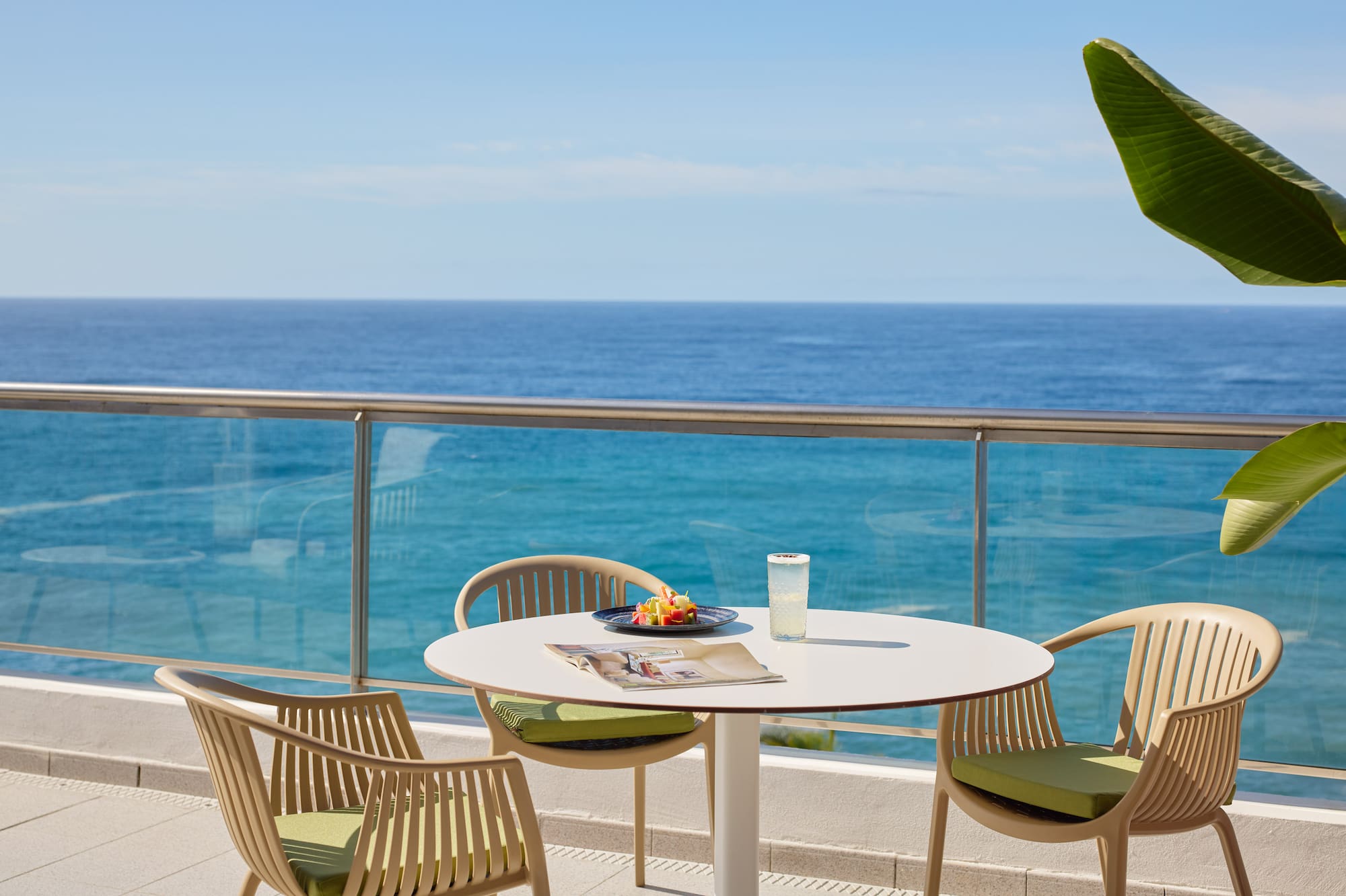 a table and chairs on a balcony overlooking the ocean