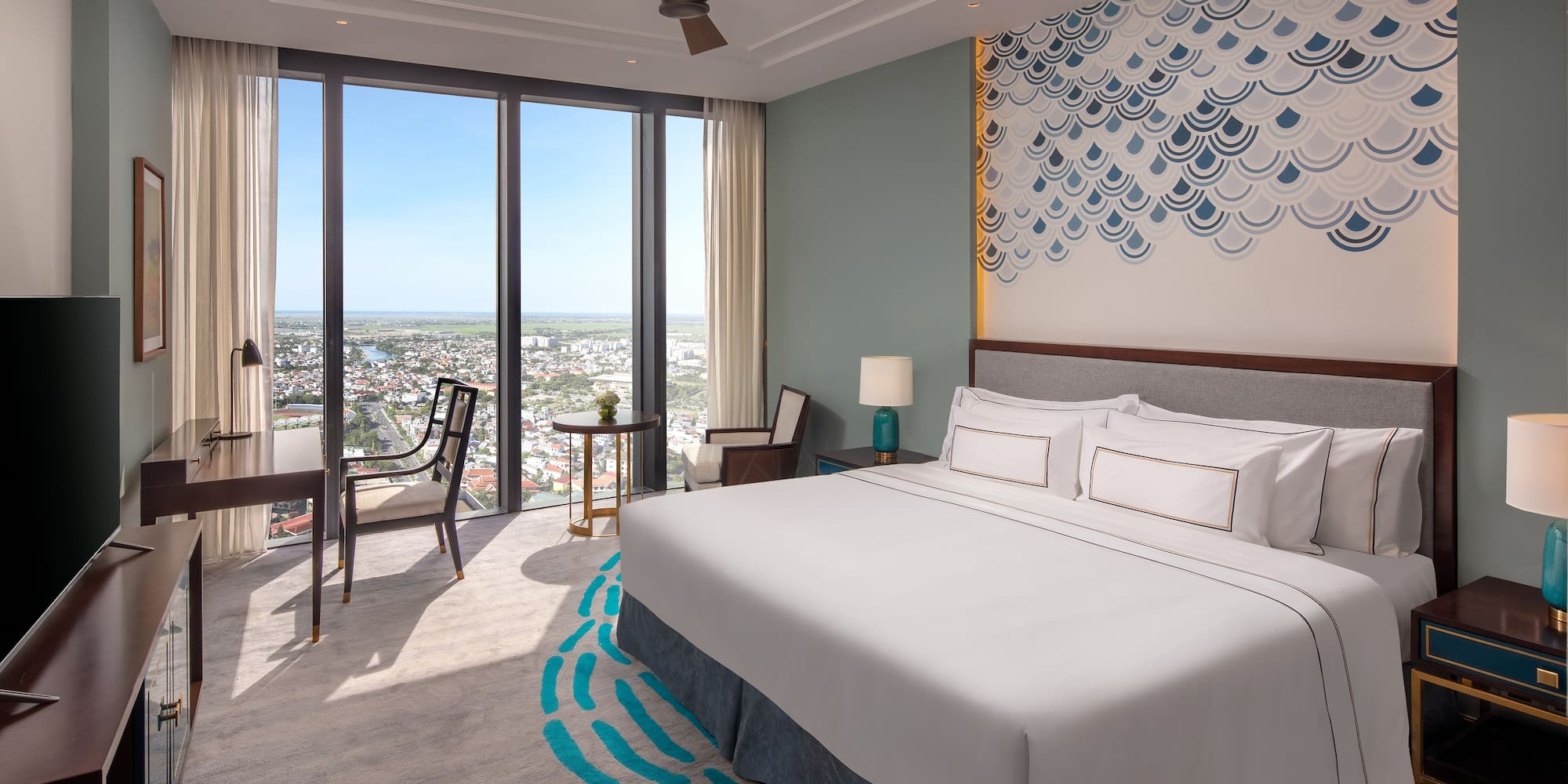 a room with a bed and chairs and a large window