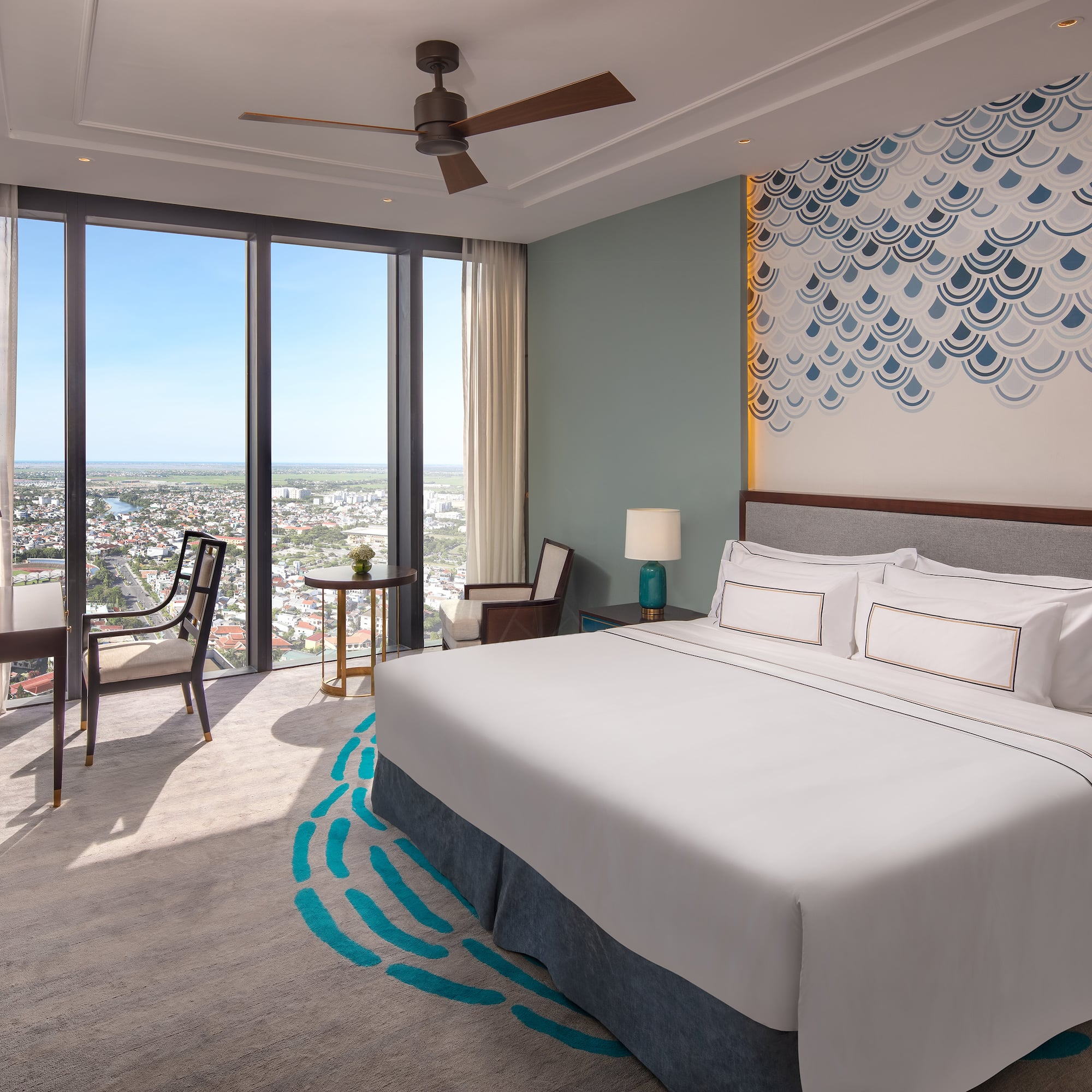 a room with a bed and chairs and a large window