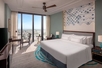 a room with a bed and chairs and a large window