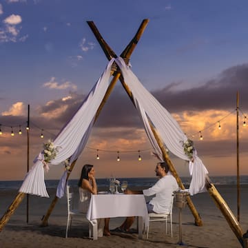 a man and woman sitting at a table on a beach