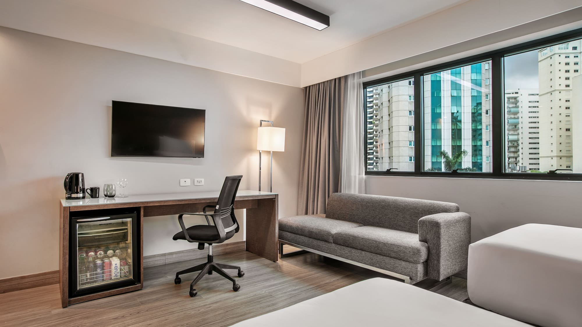 Quarto de hotel moderno com escrivaninha, TV, frigobar e sofá-cama. - Deluxe Room Twin - Meliá Ibirapuera, São Paulo