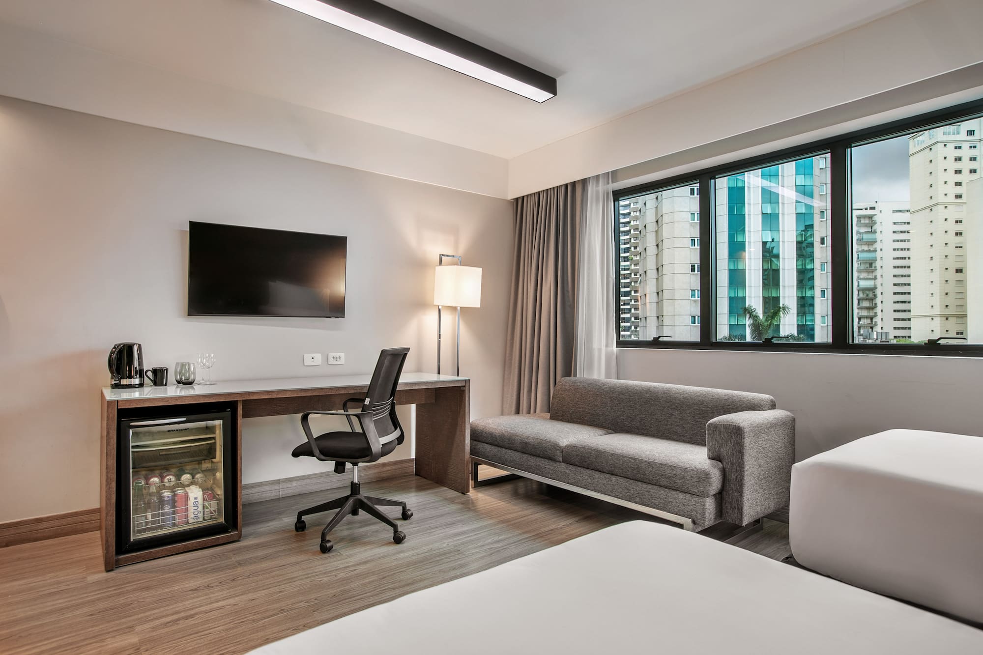 Quarto de hotel moderno com escrivaninha, TV, frigobar e sofá-cama. - Deluxe Room Twin - Meliá Ibirapuera, São Paulo