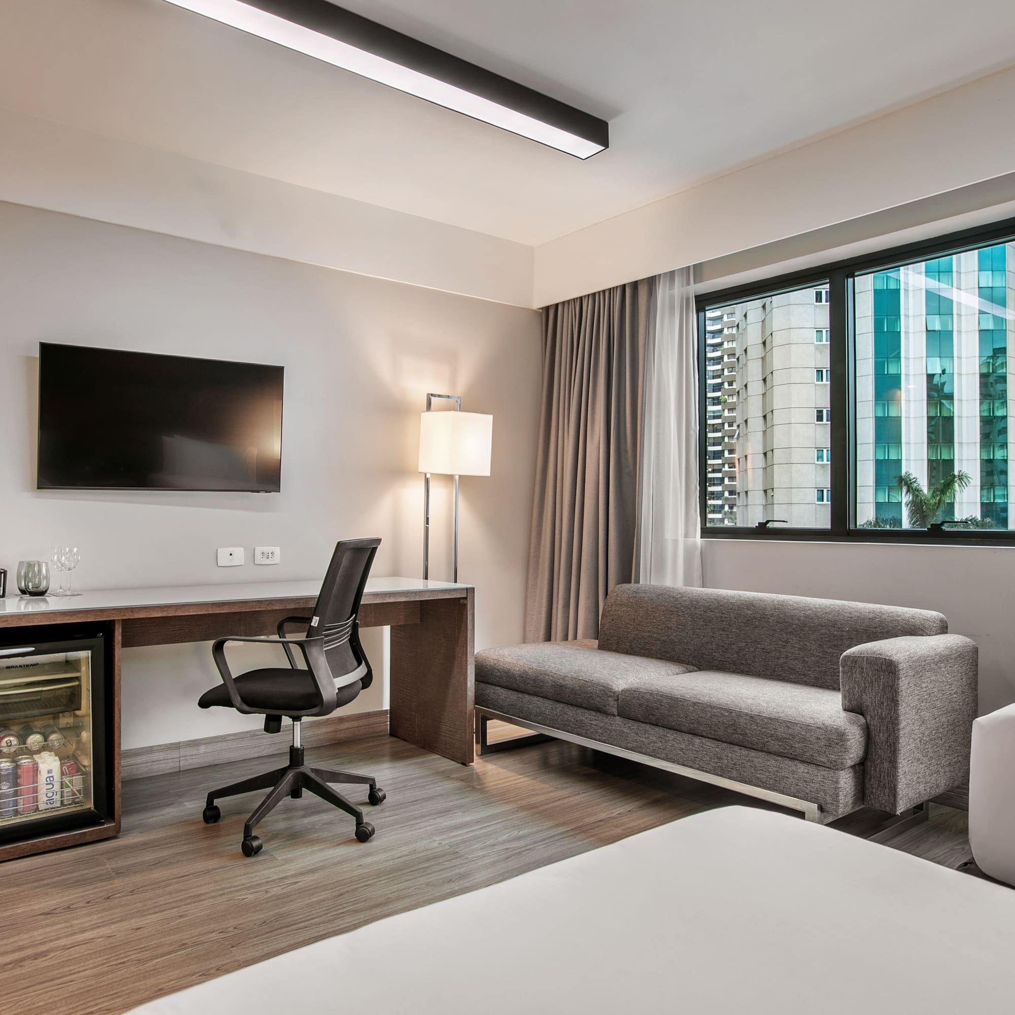 Quarto de hotel moderno com escrivaninha, TV, frigobar e sofá-cama. - Deluxe Room Twin - Meliá Ibirapuera, São Paulo