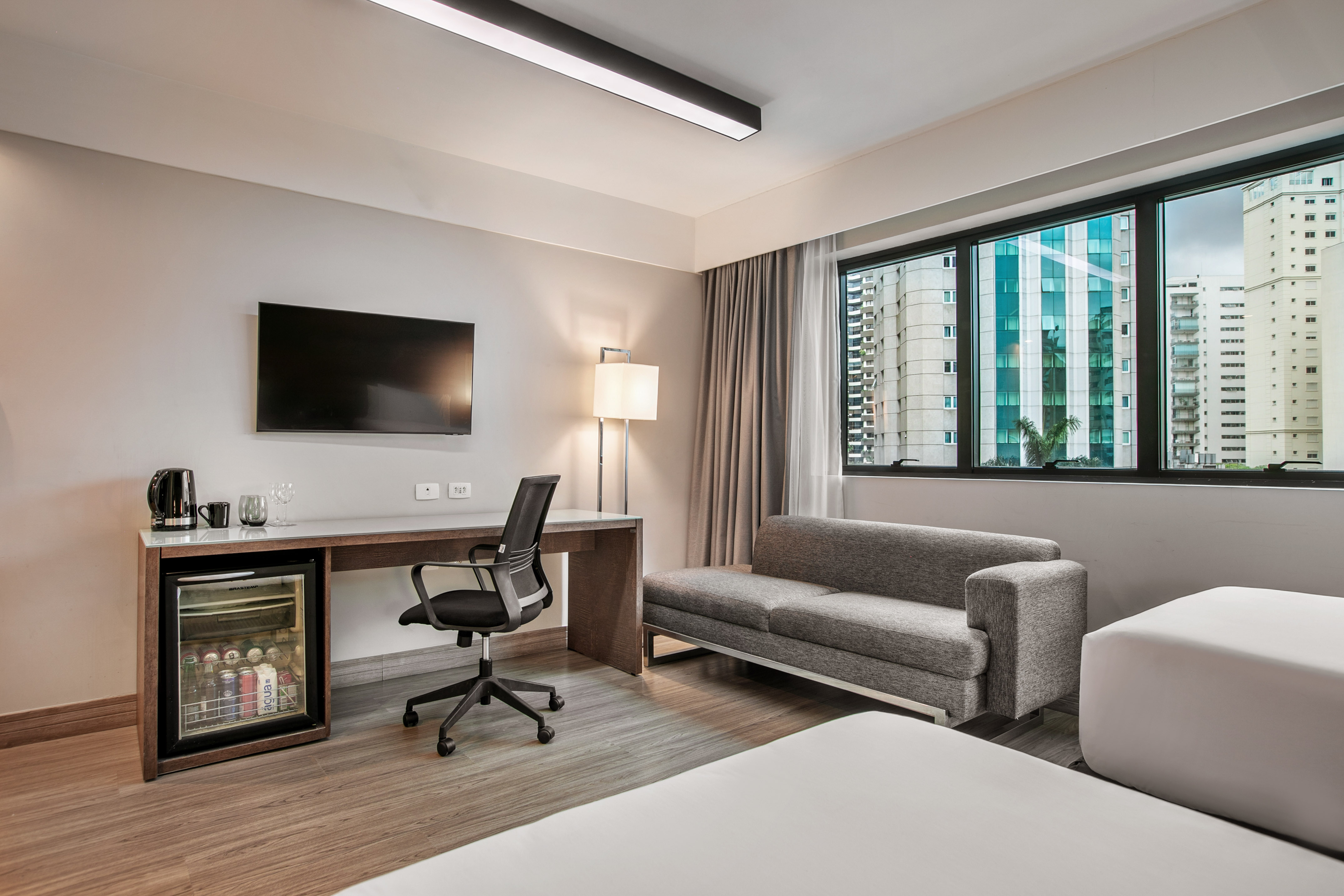 Quarto de hotel moderno com escrivaninha, TV, frigobar e sofá-cama. - Deluxe Room Twin - Meliá Ibirapuera, São Paulo