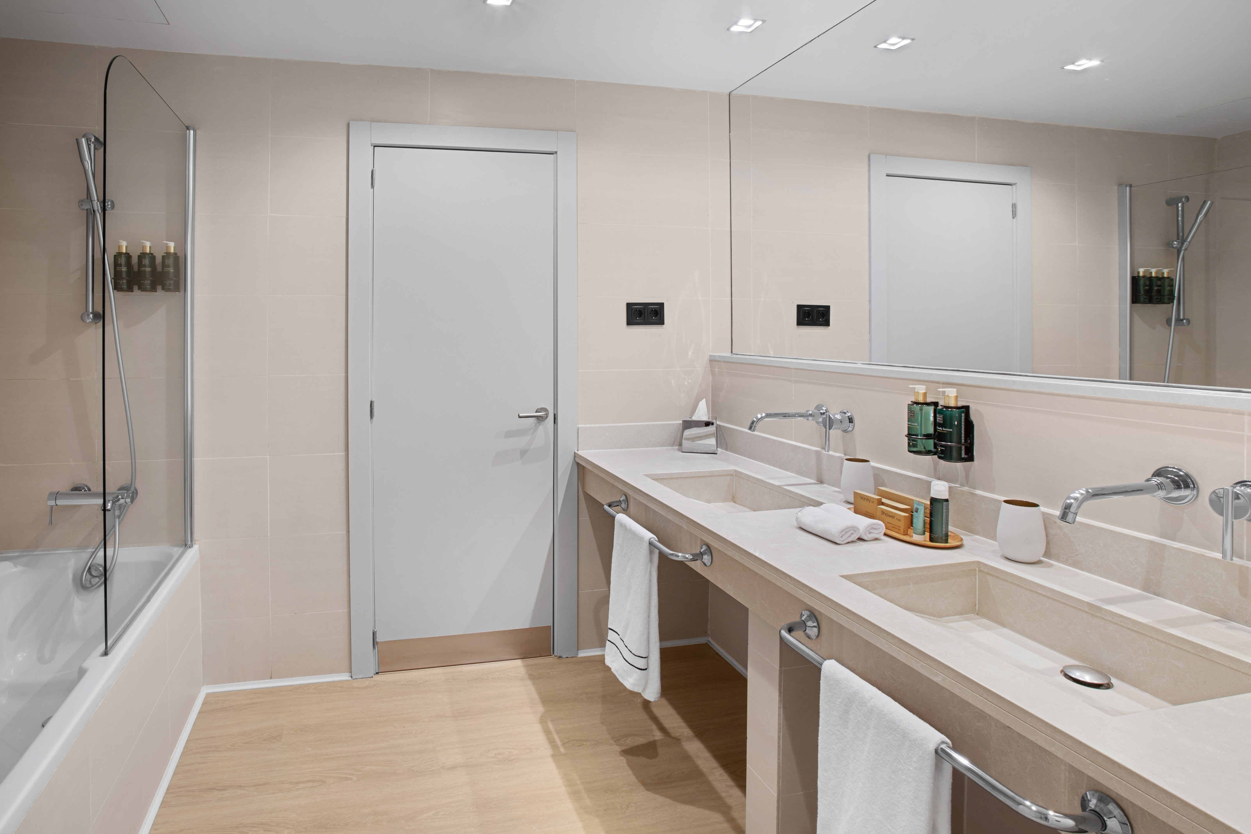 Modern bathroom with double vanity, sleek mirror, and bathtub shower combo.