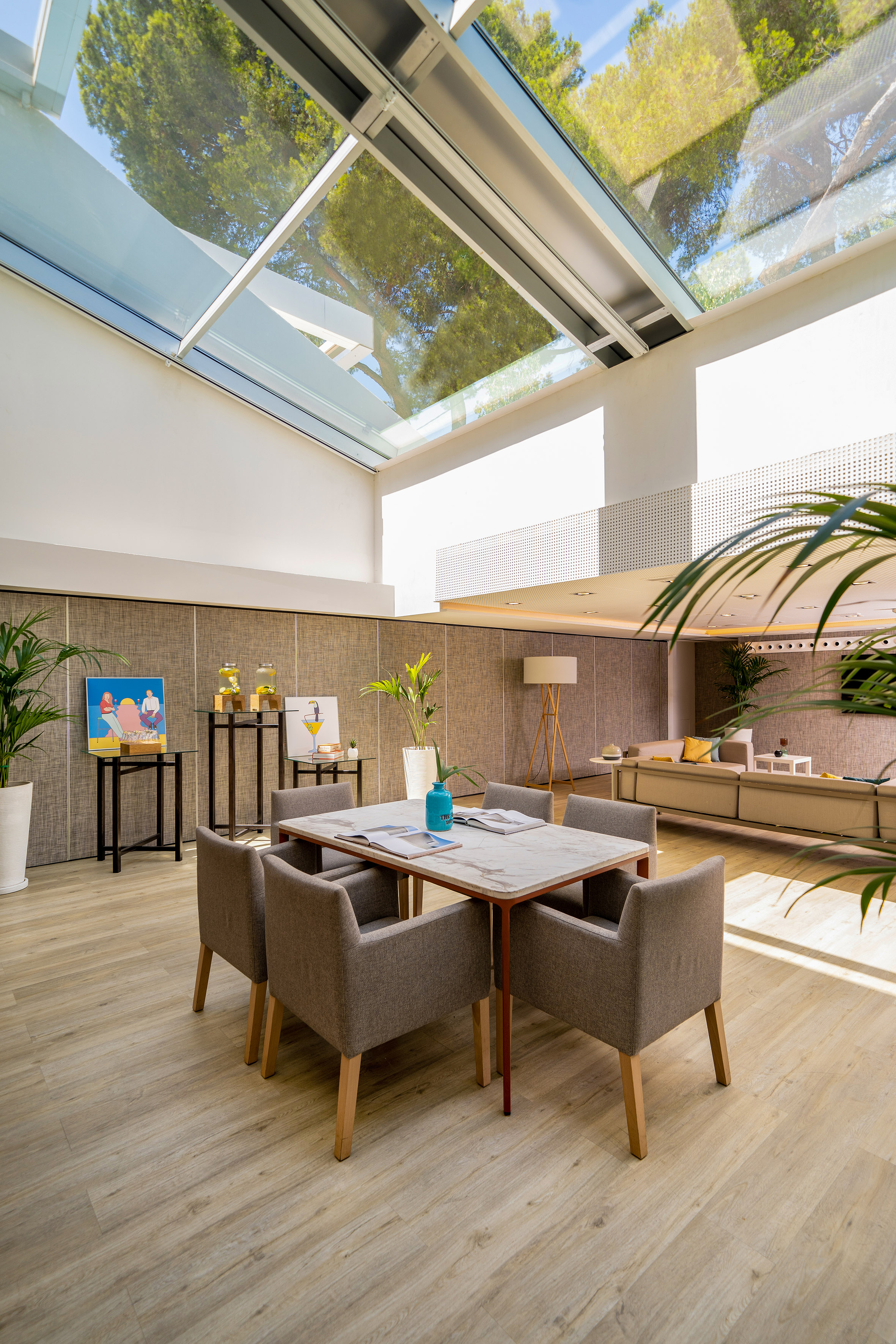 Sunlit modern lounge with glass roof, dining table, and contemporary decor.