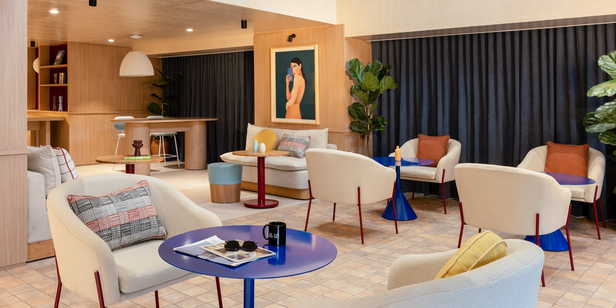 Modern lounge area with cream armchairs, blue tables, and wood paneling.