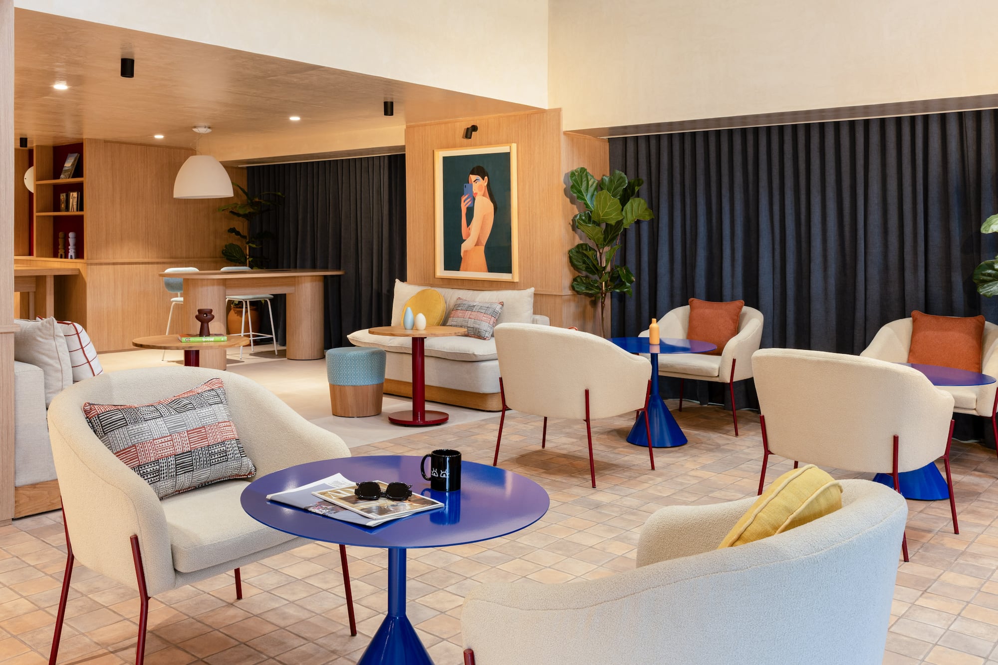Modern lounge area with cream armchairs, blue tables, and wood paneling.