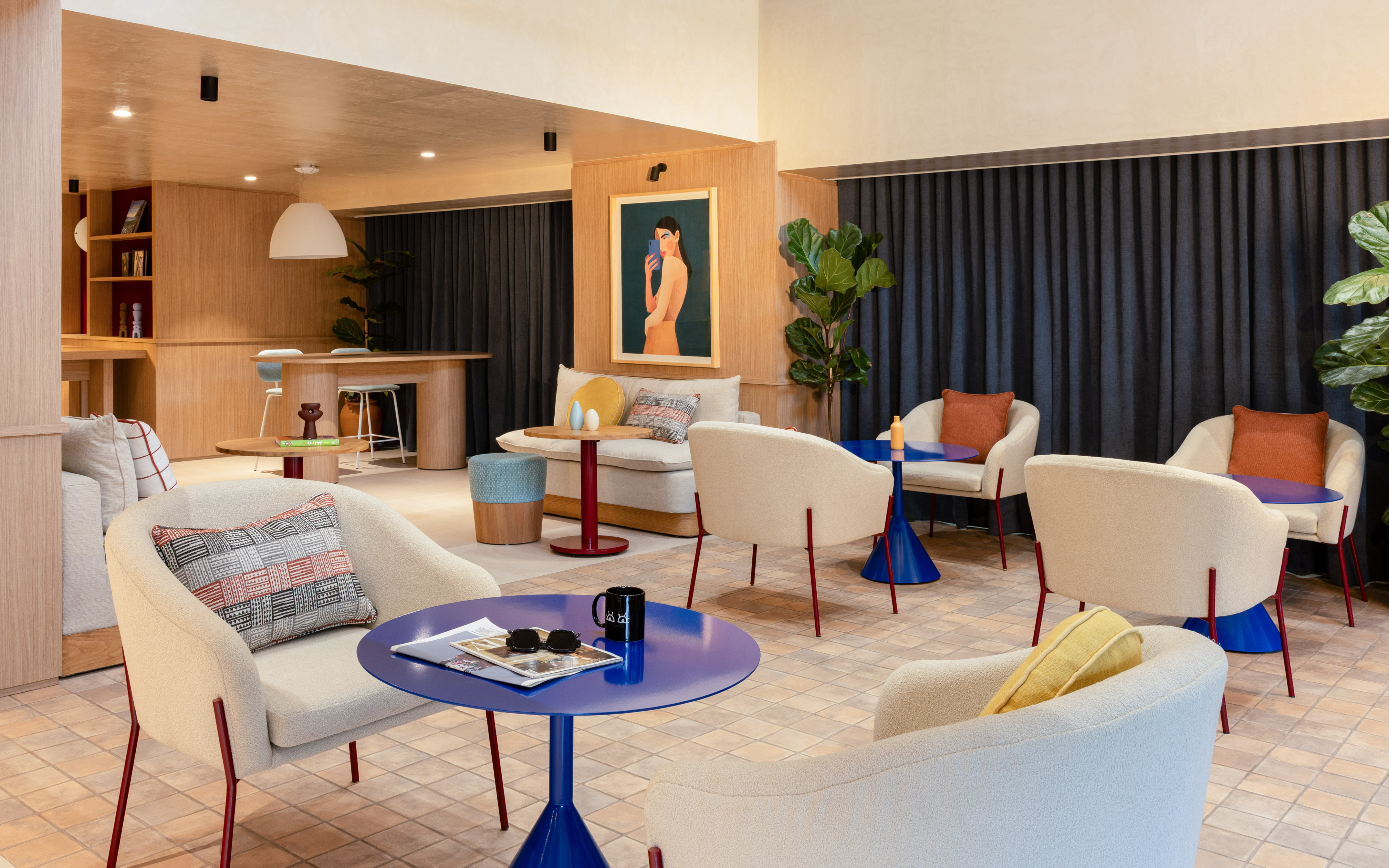 Modern lounge area with cream armchairs, blue tables, and wood paneling.