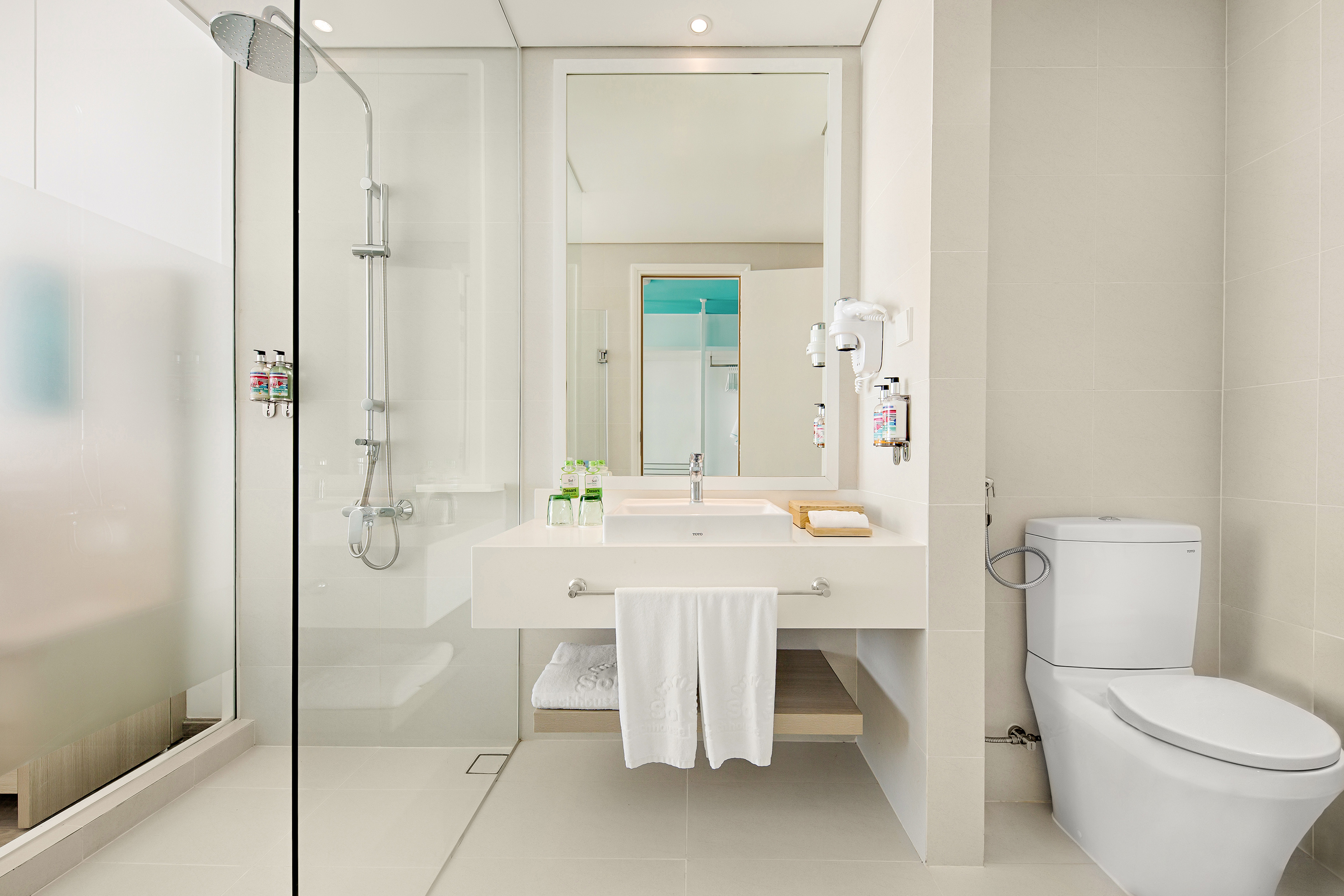 Clean, modern hotel bathroom with walk-in shower, vanity, mirror, and toilet.