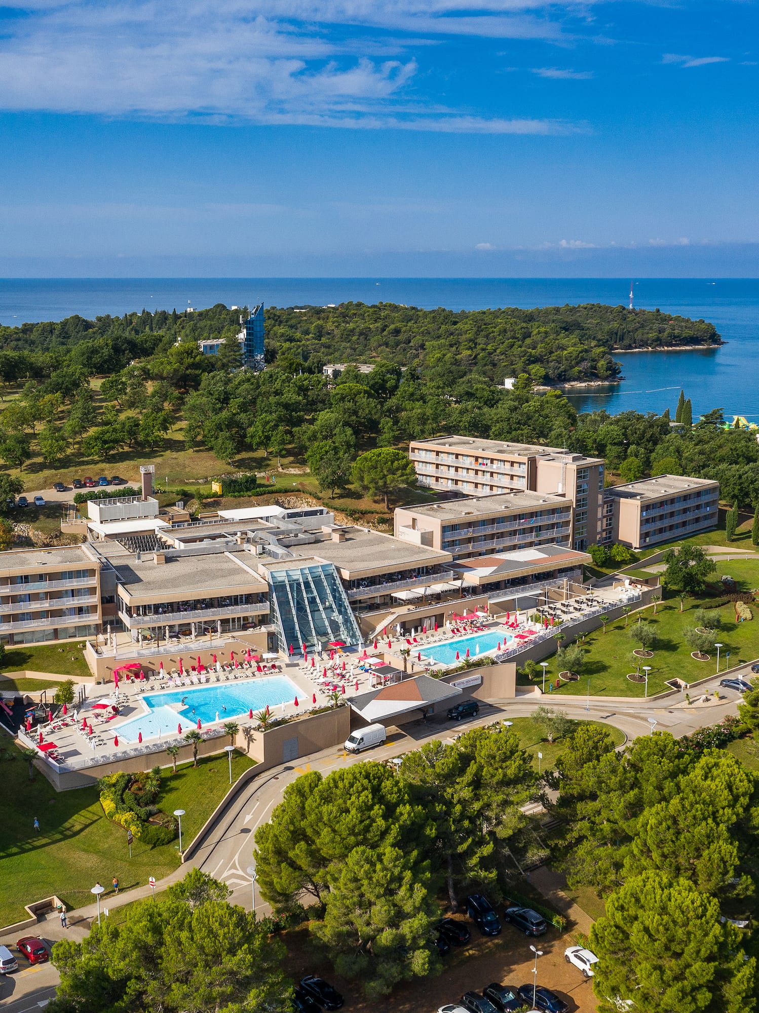 a building with a pool and trees and water in the background