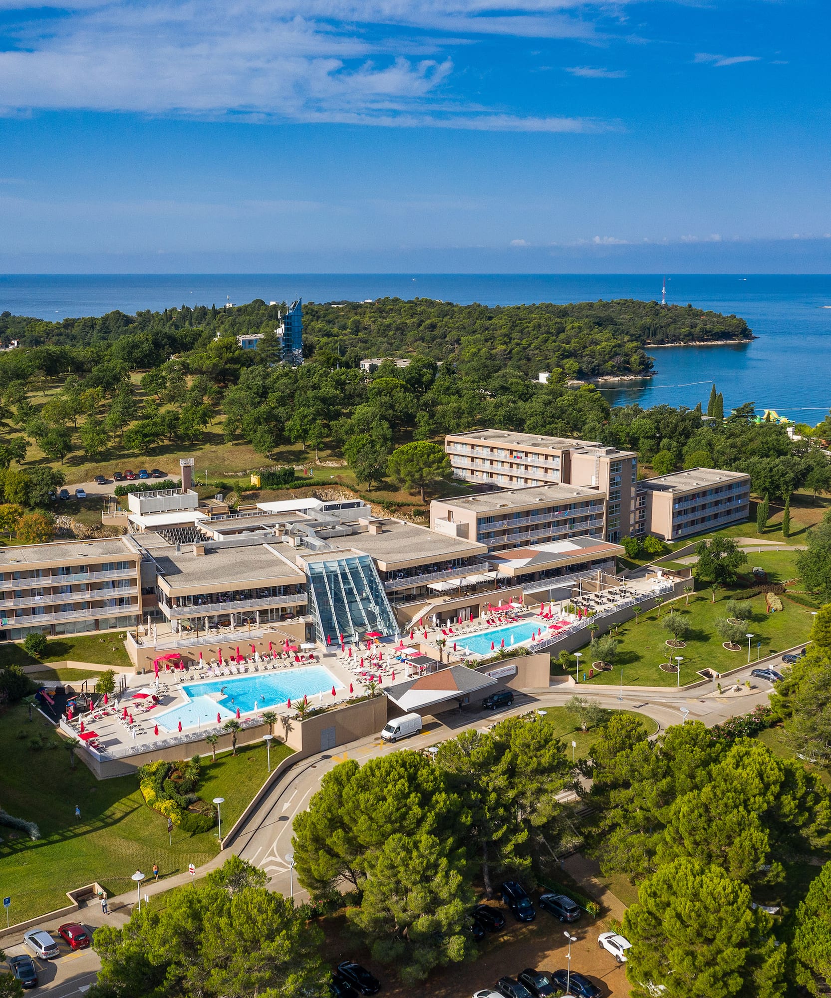 a building with a pool and trees and water in the background