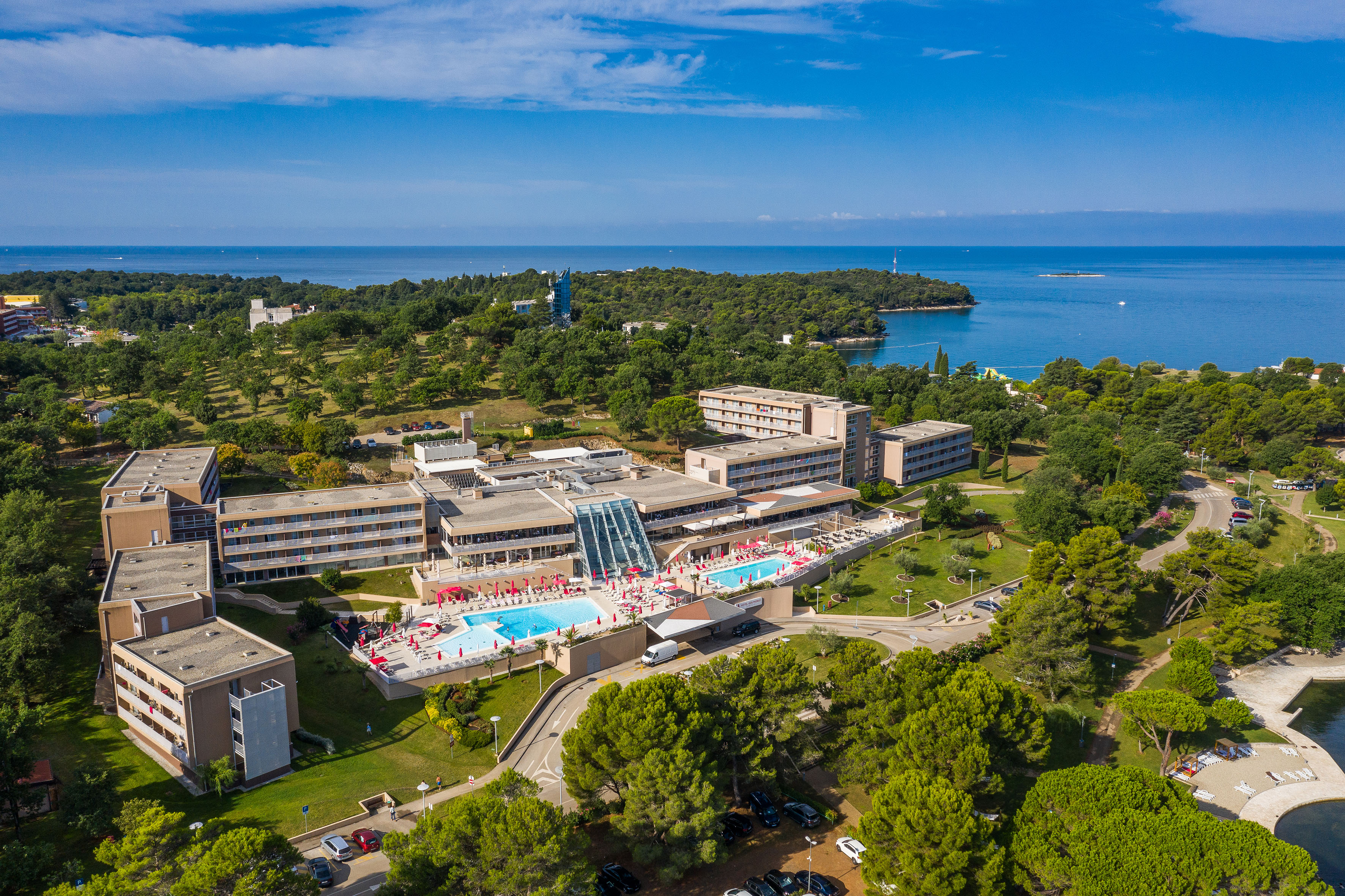 a building with a pool and trees and water in the background