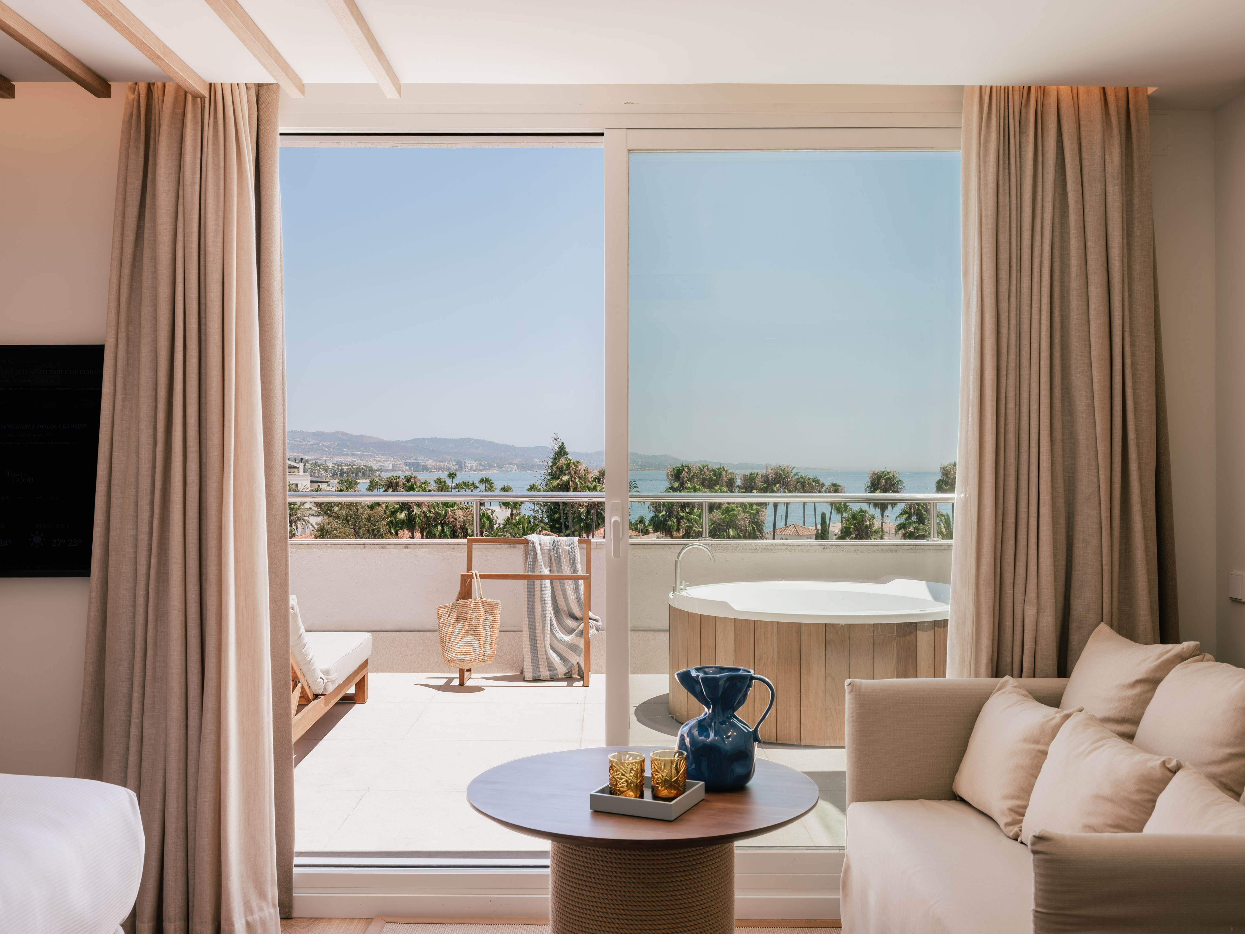 Modern hotel room with sea view balcony and private outdoor jacuzzi.