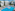Sunny hotel pool with blue lounge chairs, palm trees, and white buildings.
