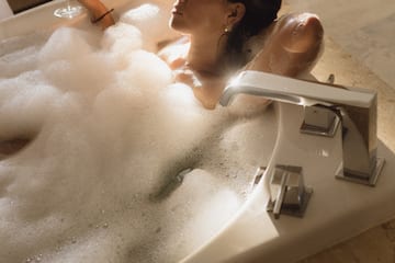 a woman in a bathtub holding a glass of wine