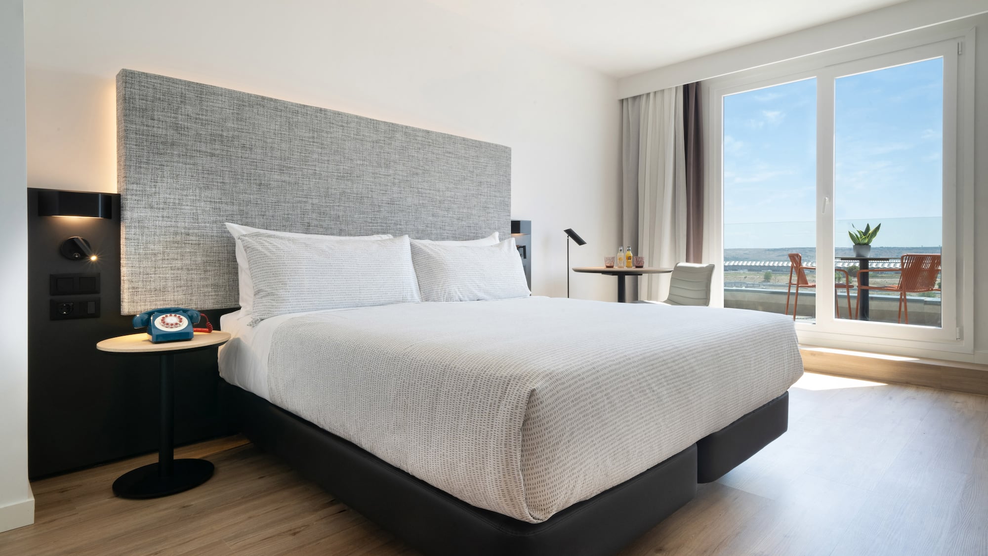 a bed with a headboard and a table in a room with a view of the ocean