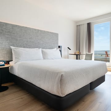 a bed with a headboard and a table in a room with a view of the ocean