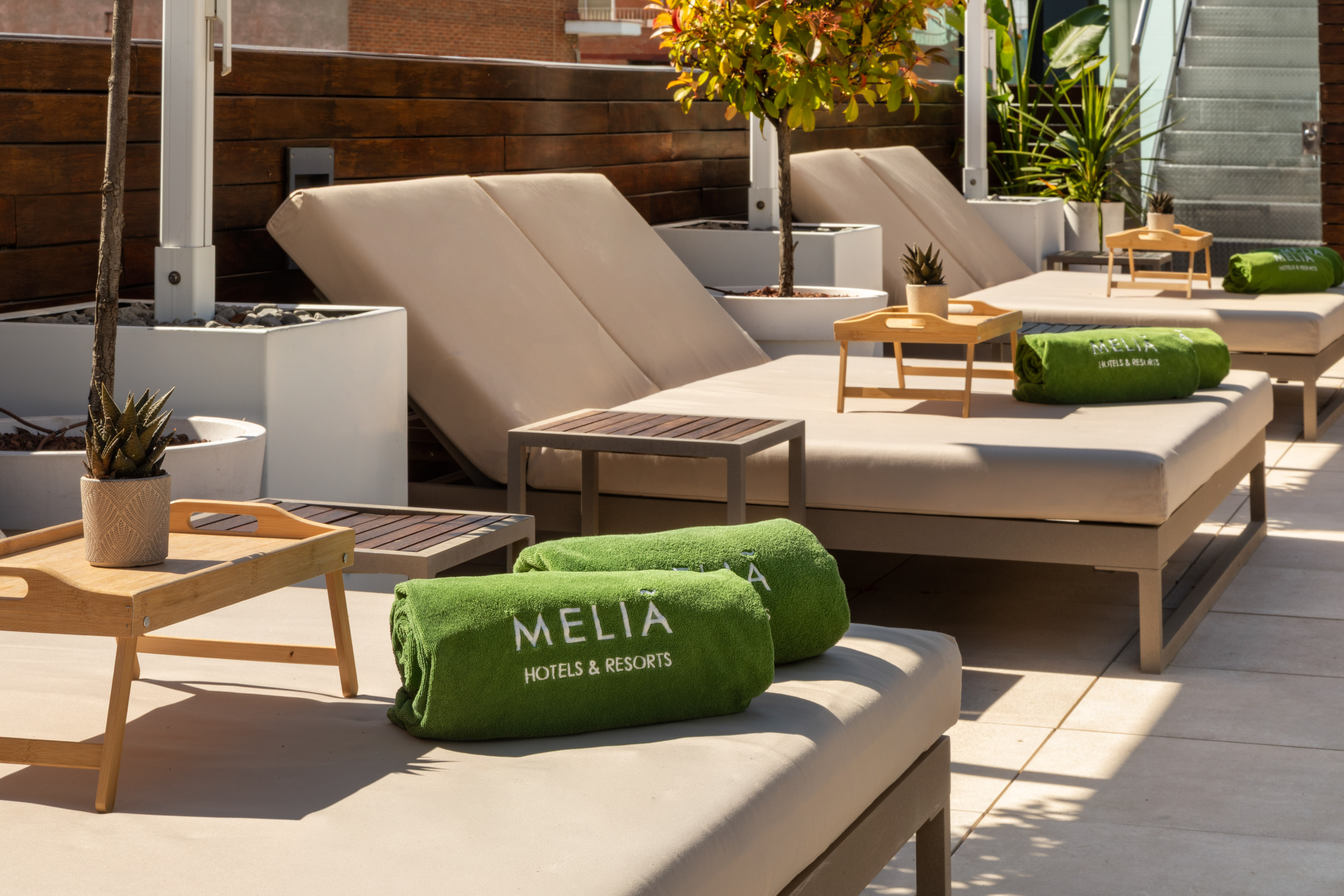 Meliá Hotels & Resorts sun loungers with green towels on a sunny rooftop terrace.