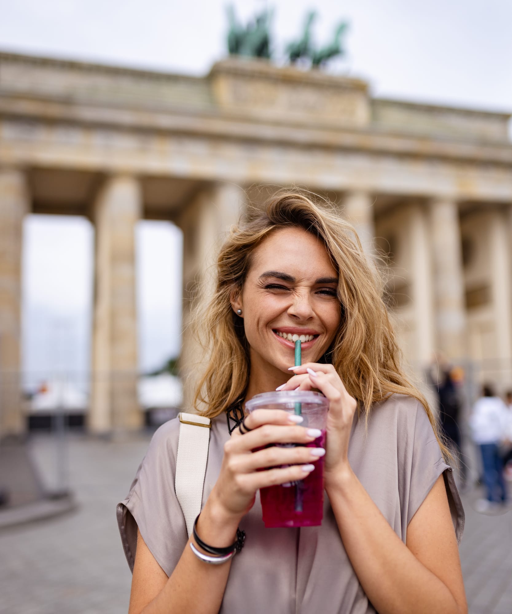 a woman smiling and drinking from a plastic cup