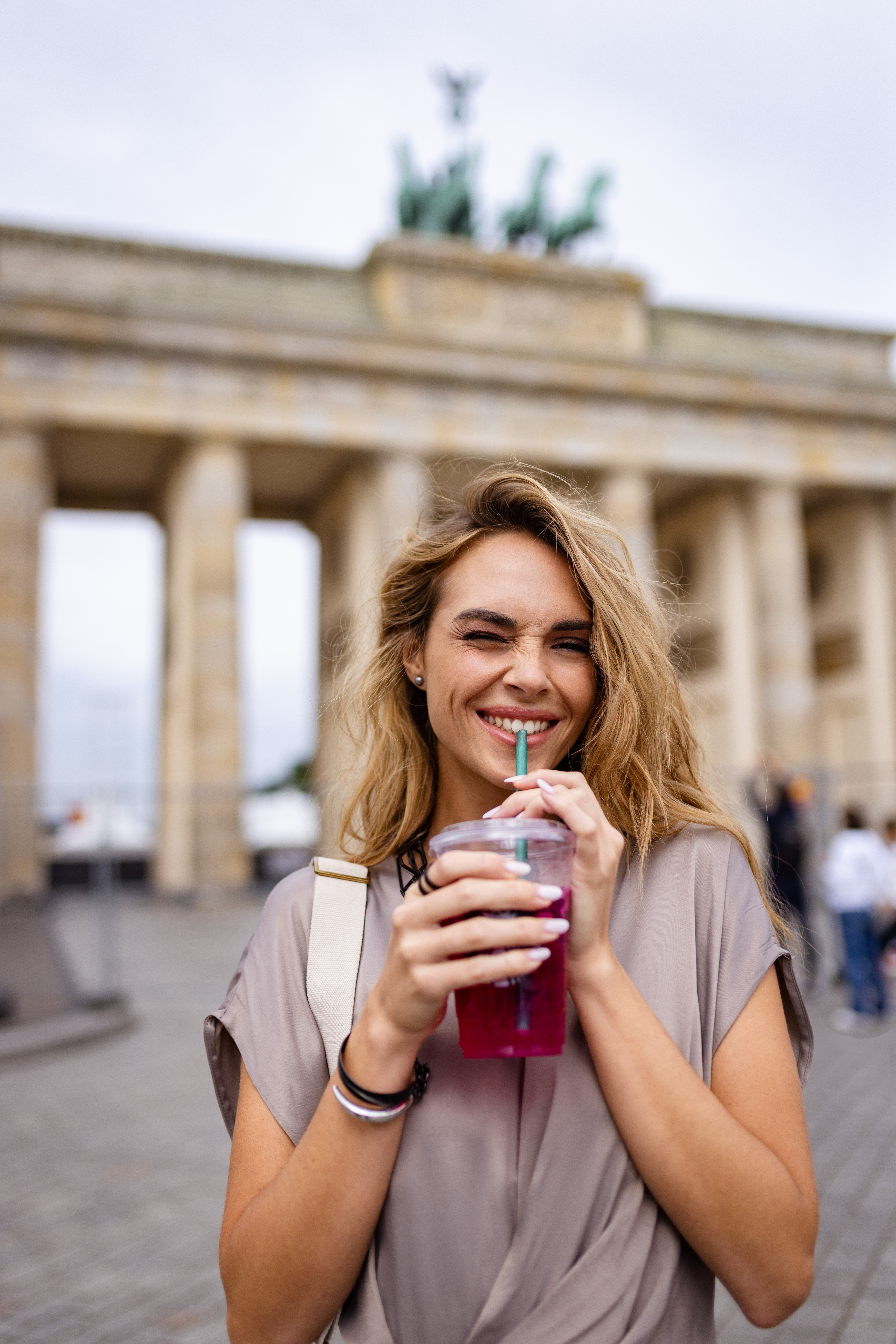 a woman smiling and drinking from a plastic cup