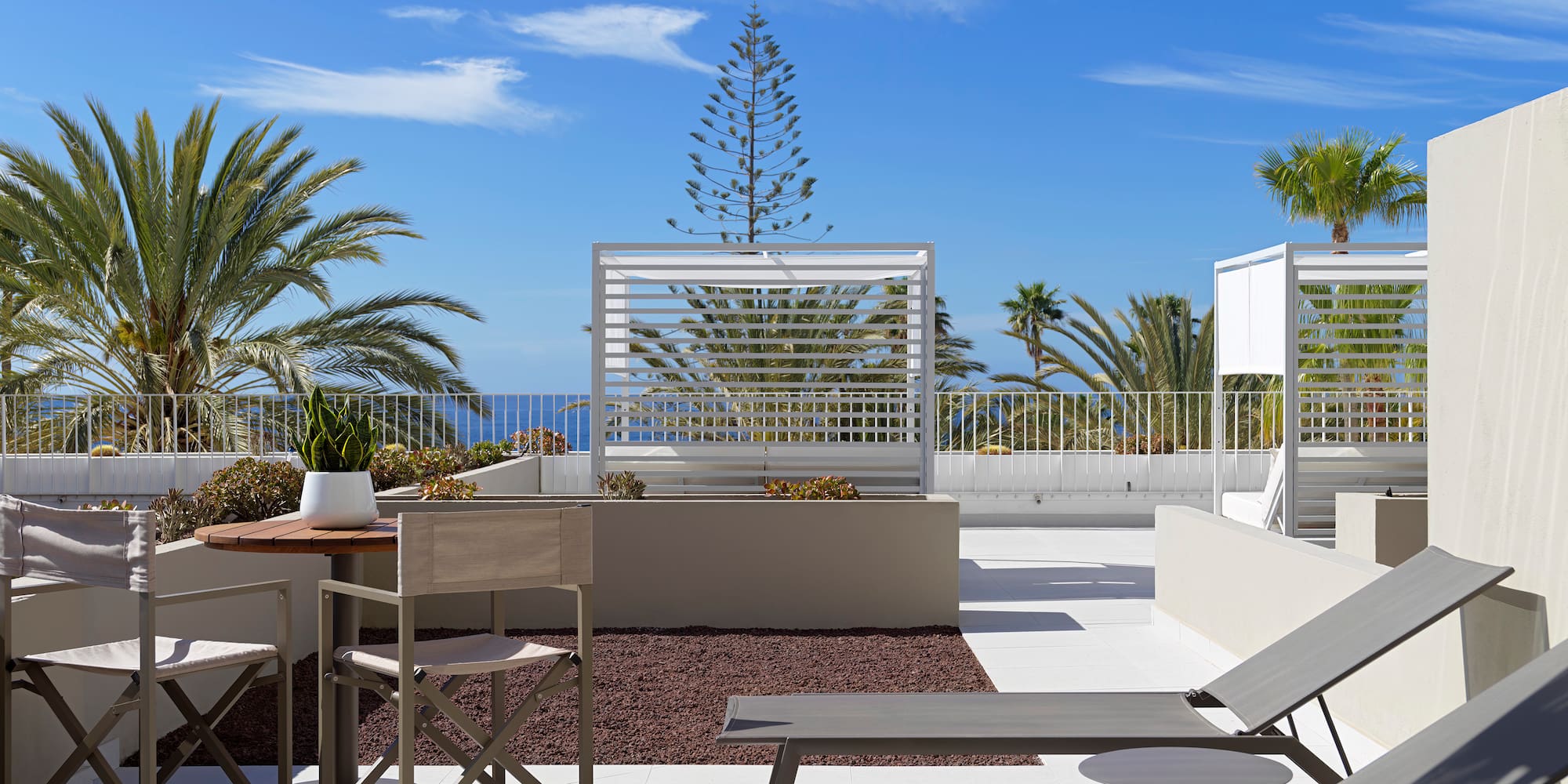 a patio with chairs and tables and plants on a sunny day
