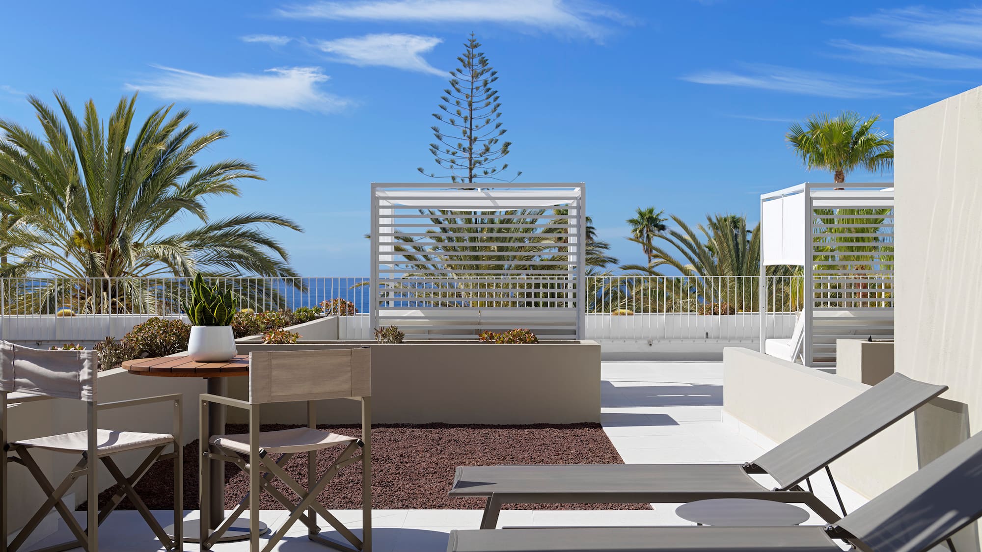 a patio with chairs and tables and plants on a sunny day