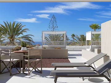 a patio with chairs and tables and plants on a sunny day