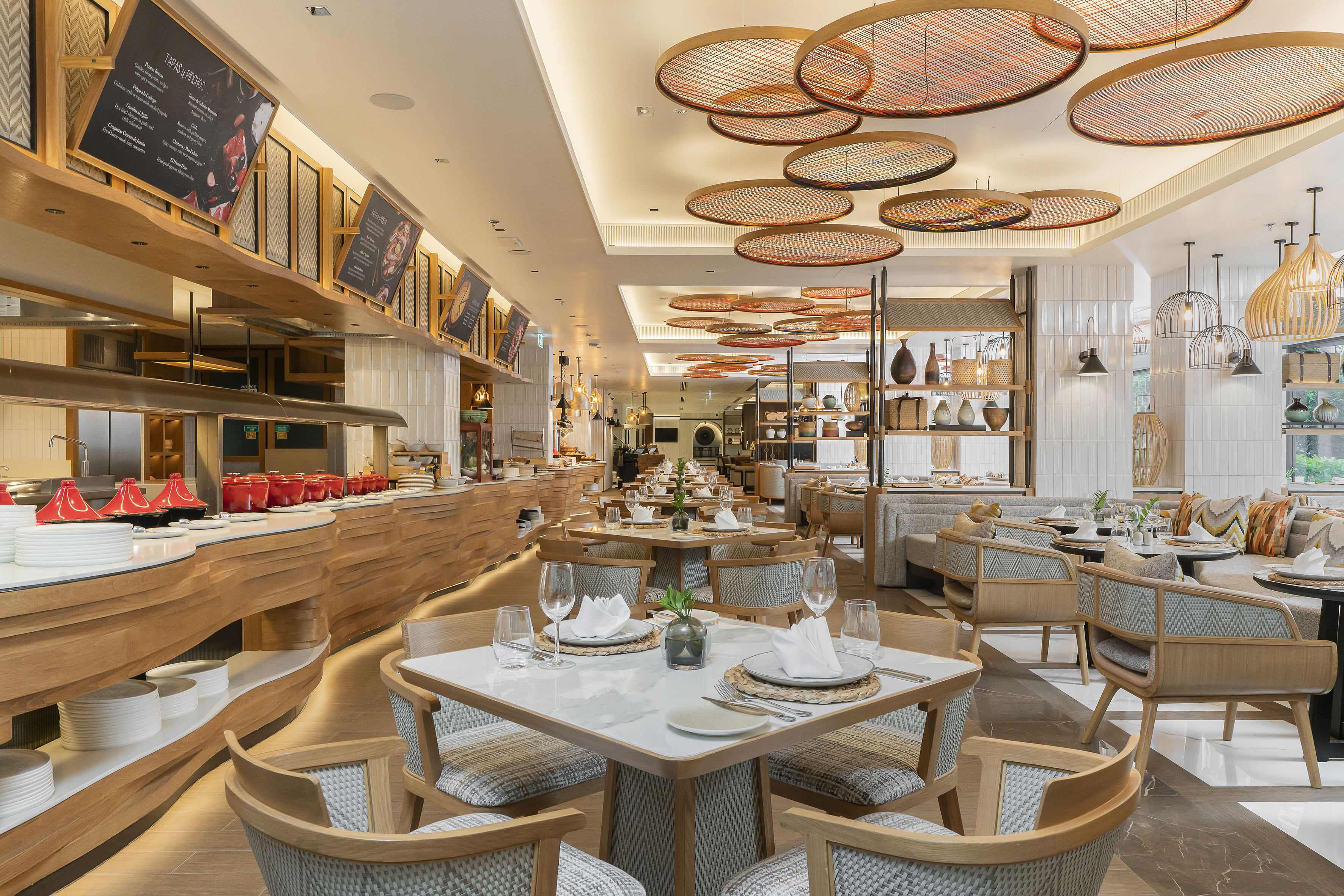 Modern restaurant dining room with buffet setup, set tables, and stylish wooden decor.