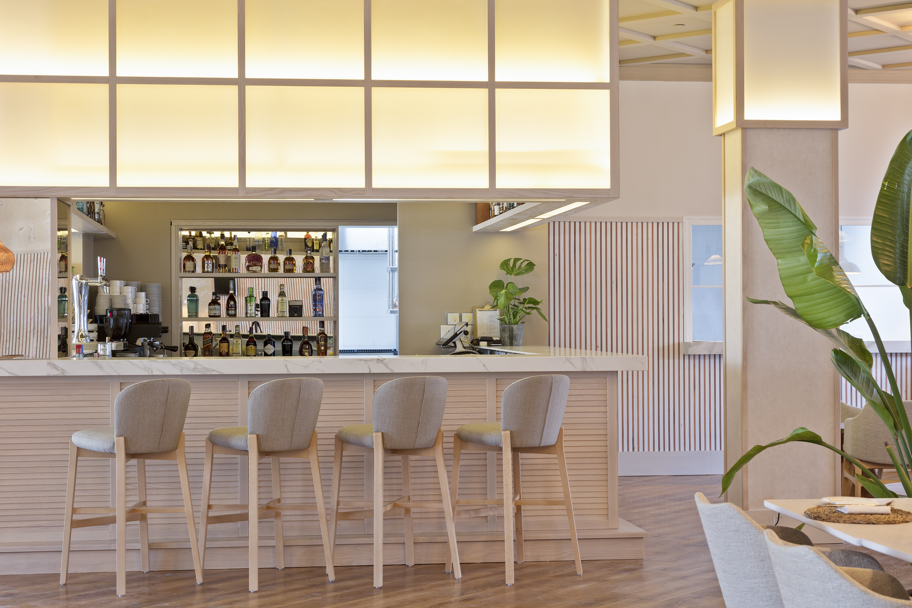 Modern bar counter with stools, liquor display, and ambient lighting.