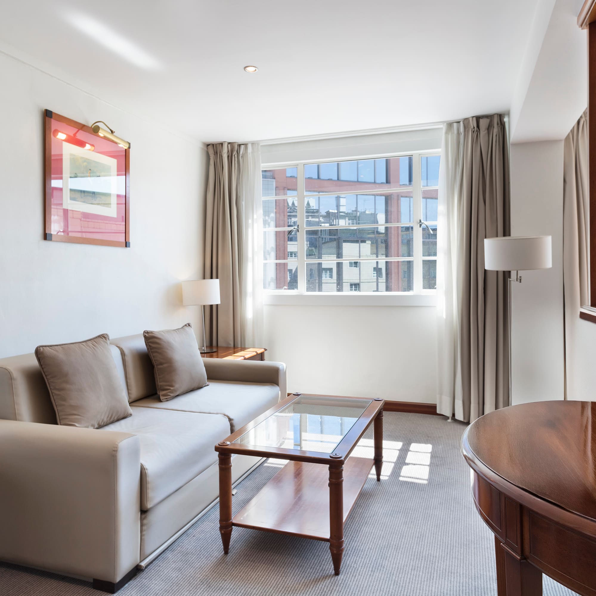 Elegant hotel living room with sofa, coffee table, and large window.
