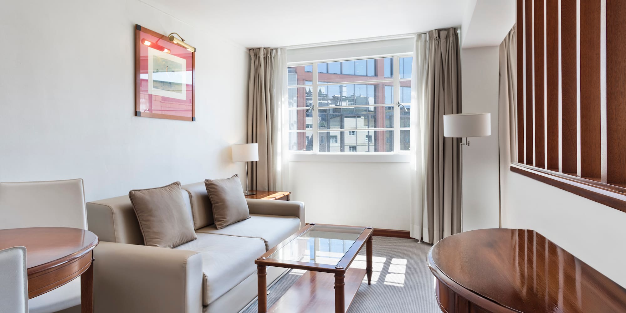 Elegant hotel living room with sofa, coffee table, and large window.