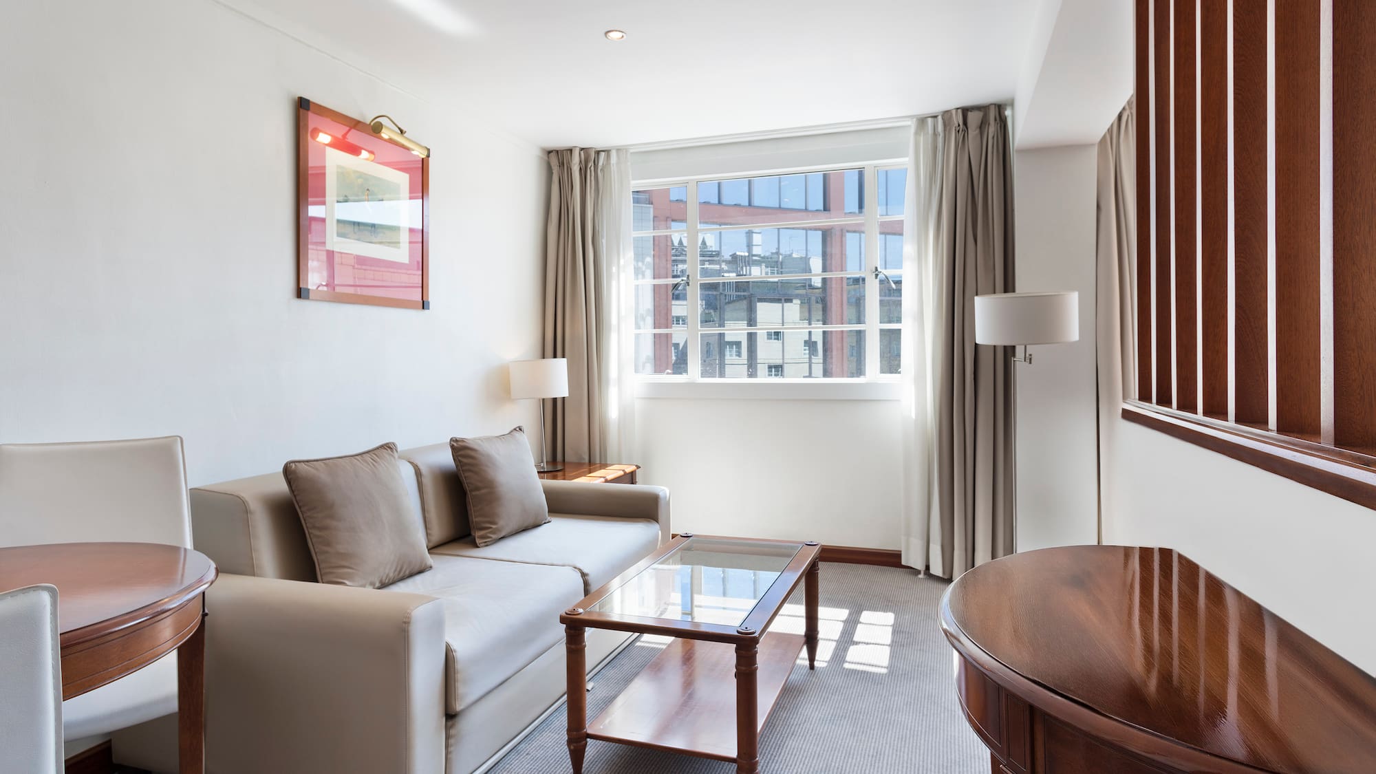 Elegant hotel living room with sofa, coffee table, and large window.