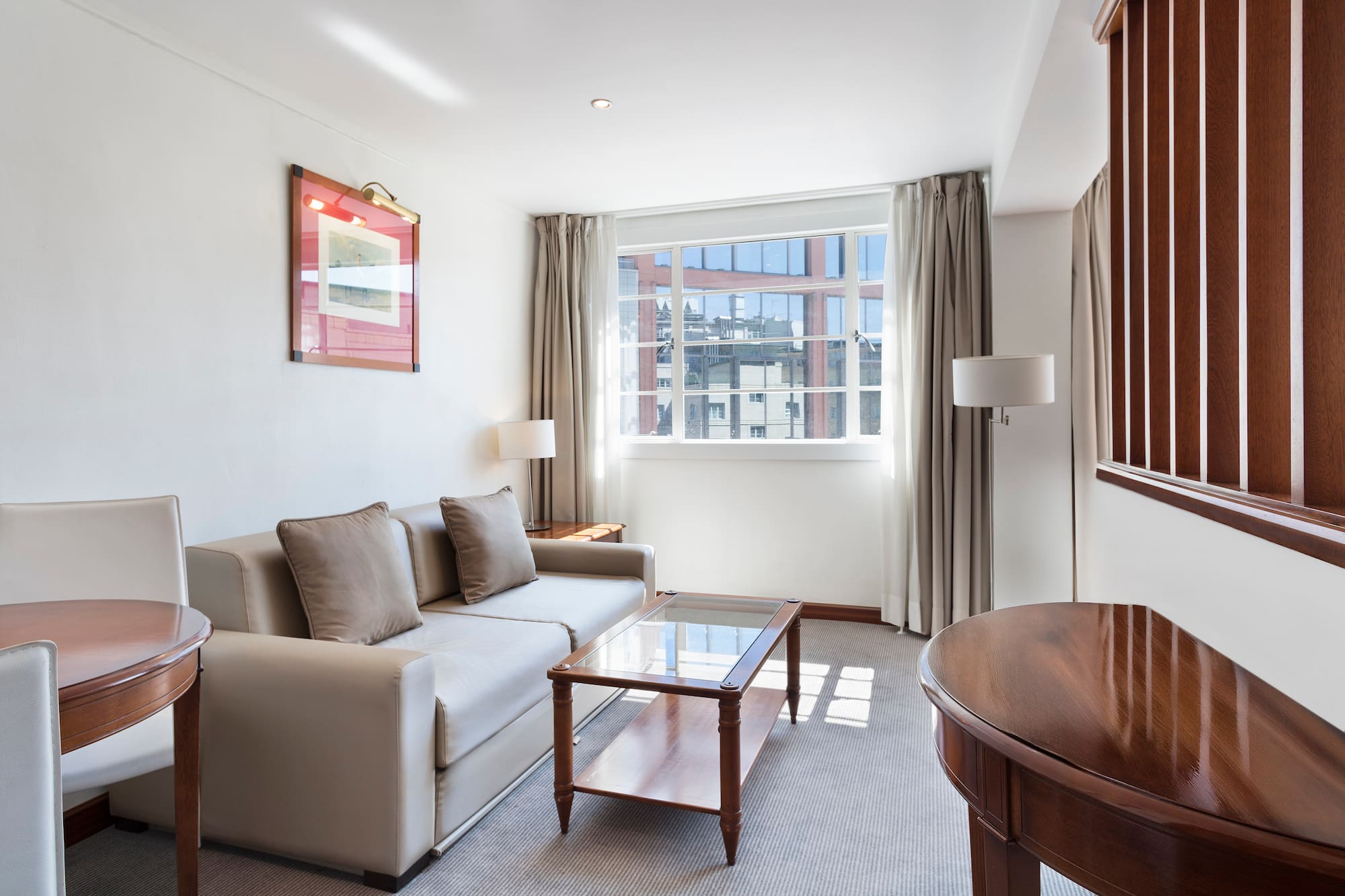 Elegant hotel living room with sofa, coffee table, and large window.