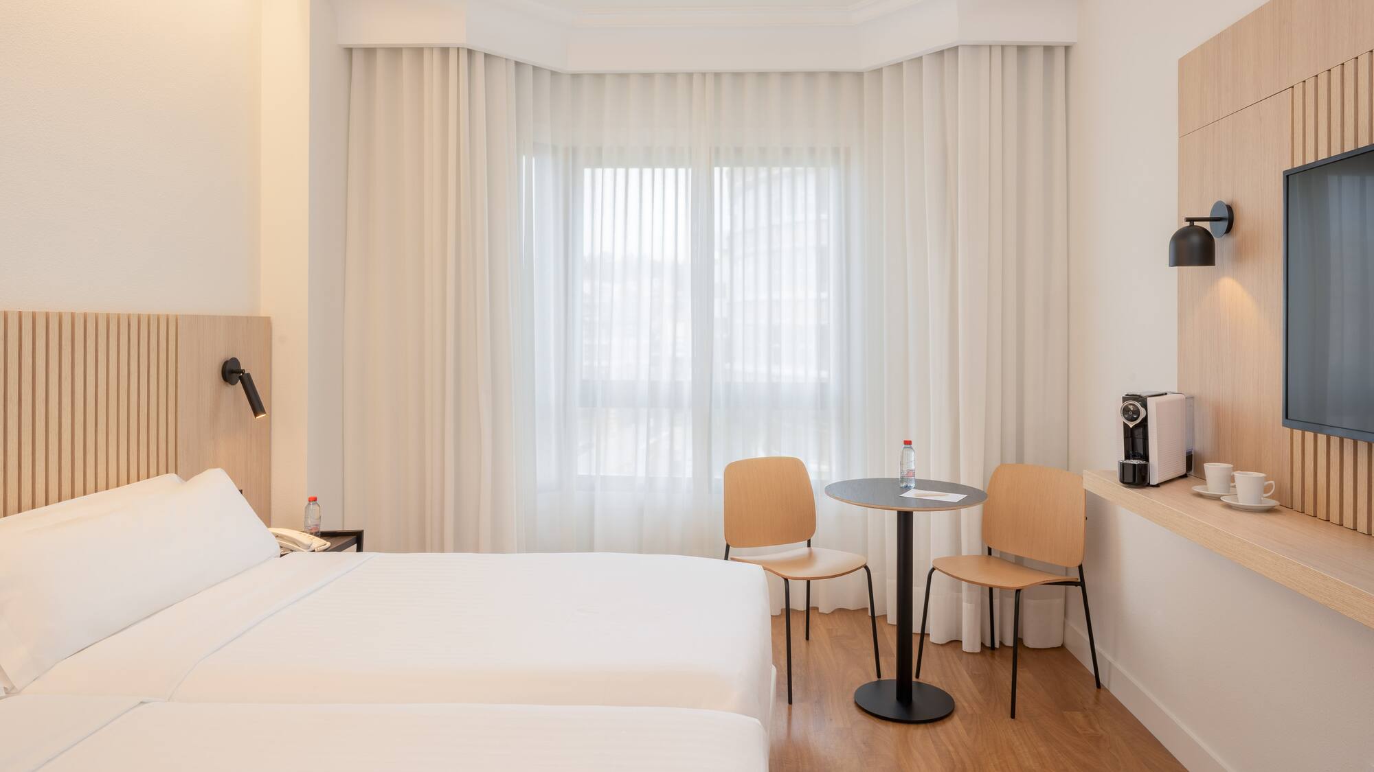 a room with two beds and a table and chairs