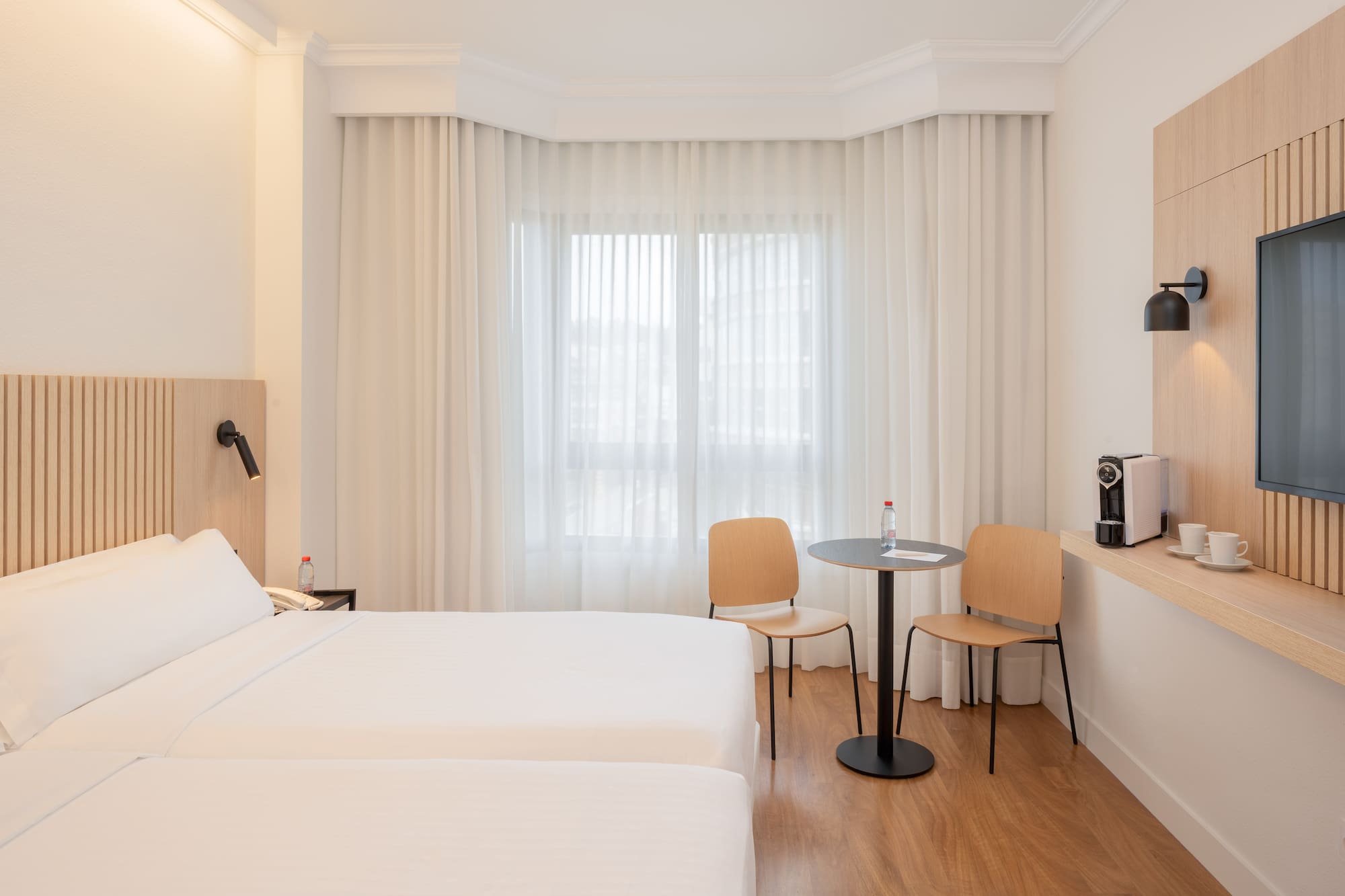 a room with two beds and a table and chairs