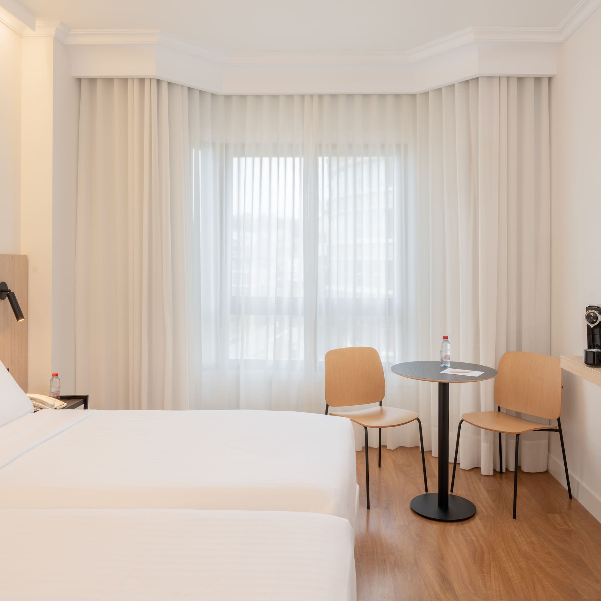 a room with two beds and a table and chairs