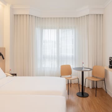 a room with two beds and a table and chairs