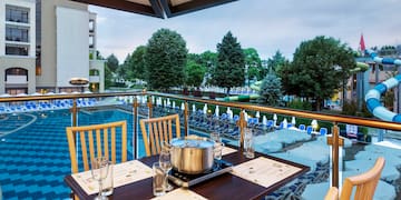 a table with chairs and a pot on it by a pool