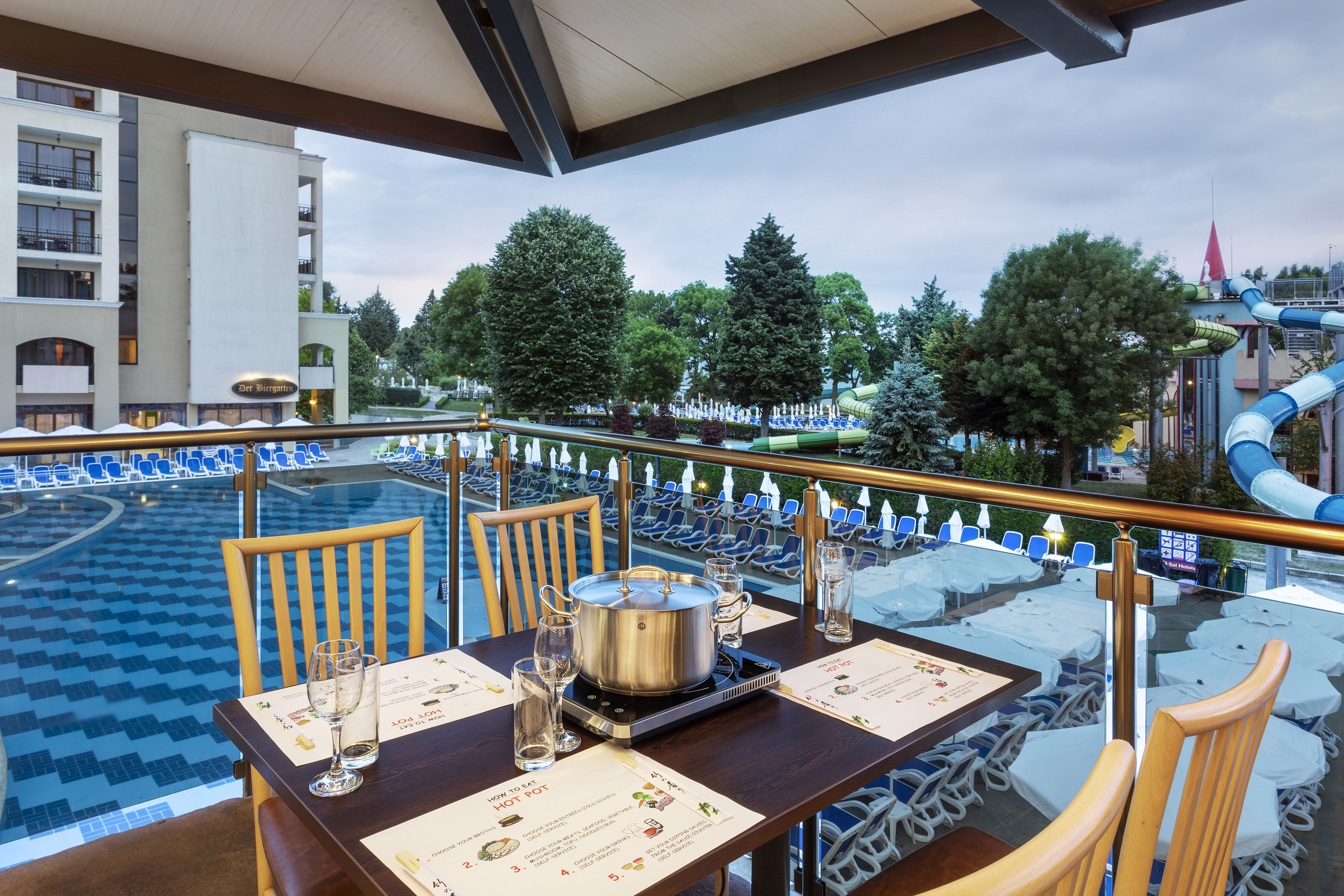 a table with chairs and a pot on it by a pool