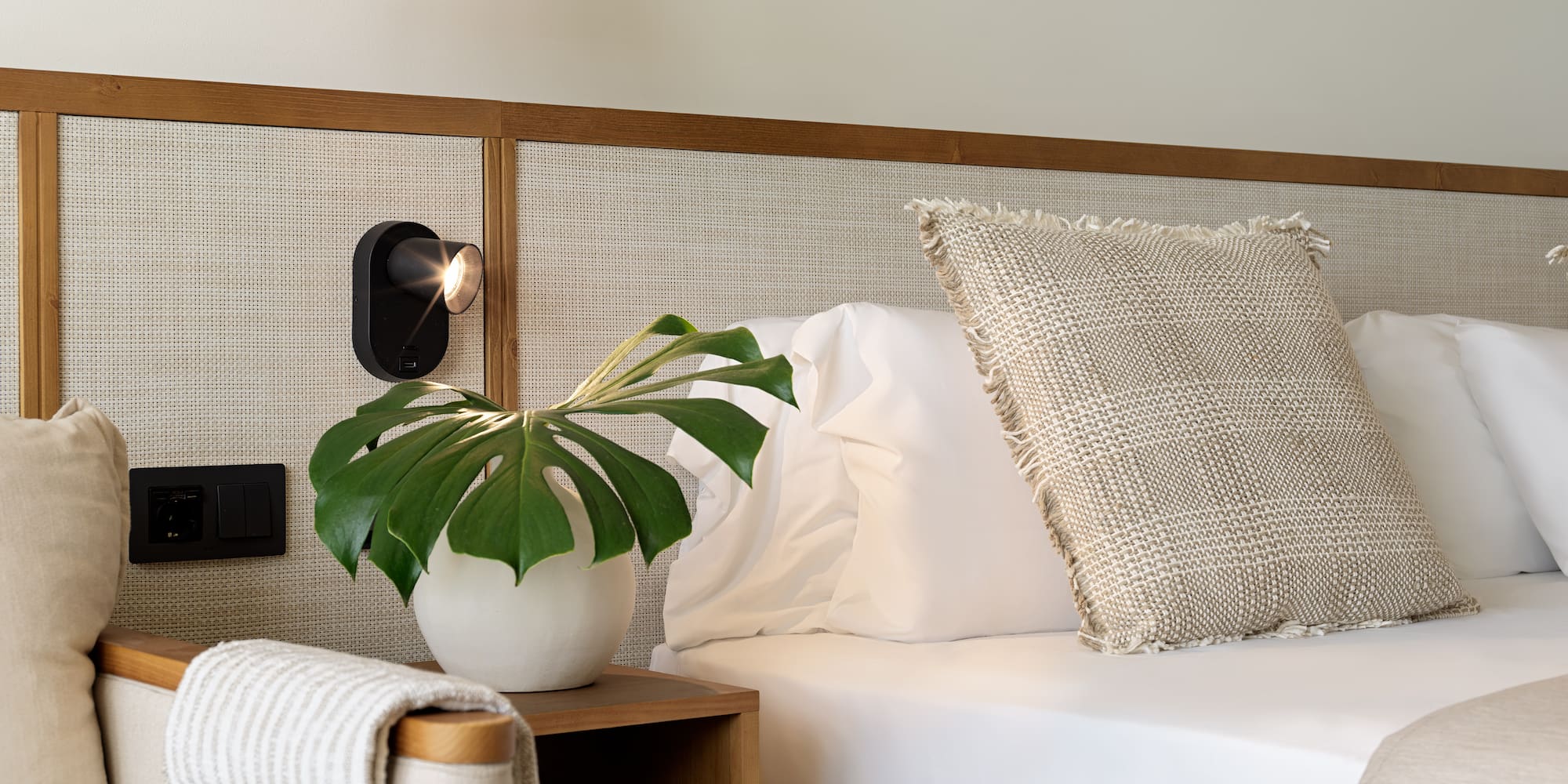 a plant on a table next to a bed