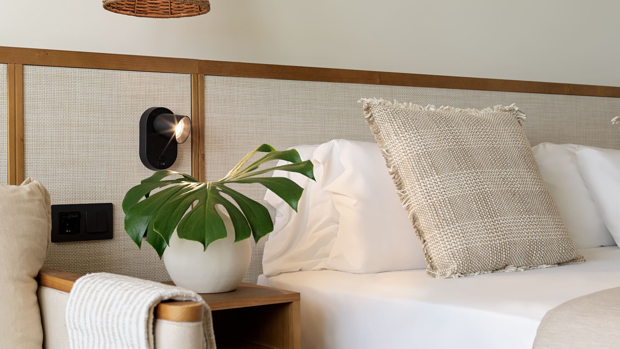 a plant on a table next to a bed