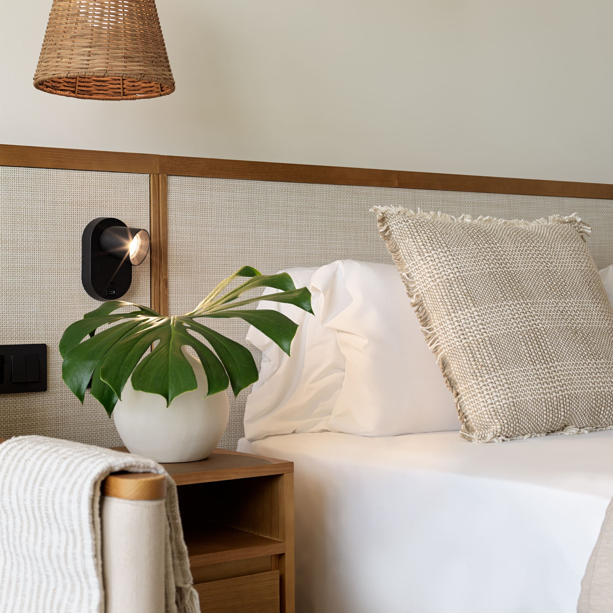 a plant on a table next to a bed