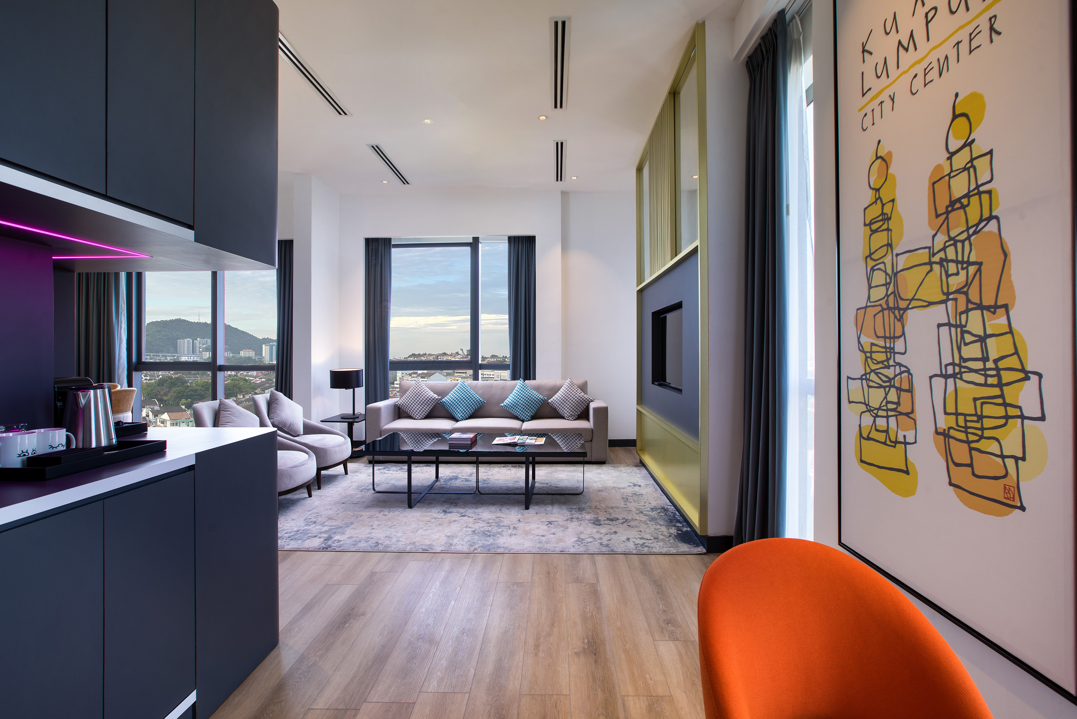 Modern Kuala Lumpur hotel suite living room, city view, and kitchenette.