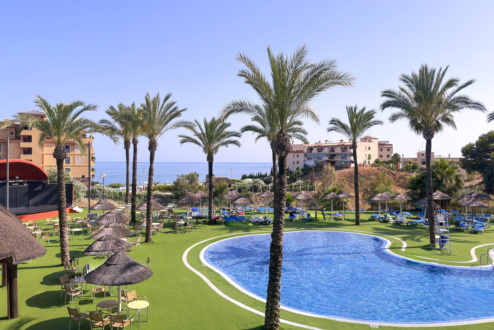 a pool with umbrellas and chairs and palm trees