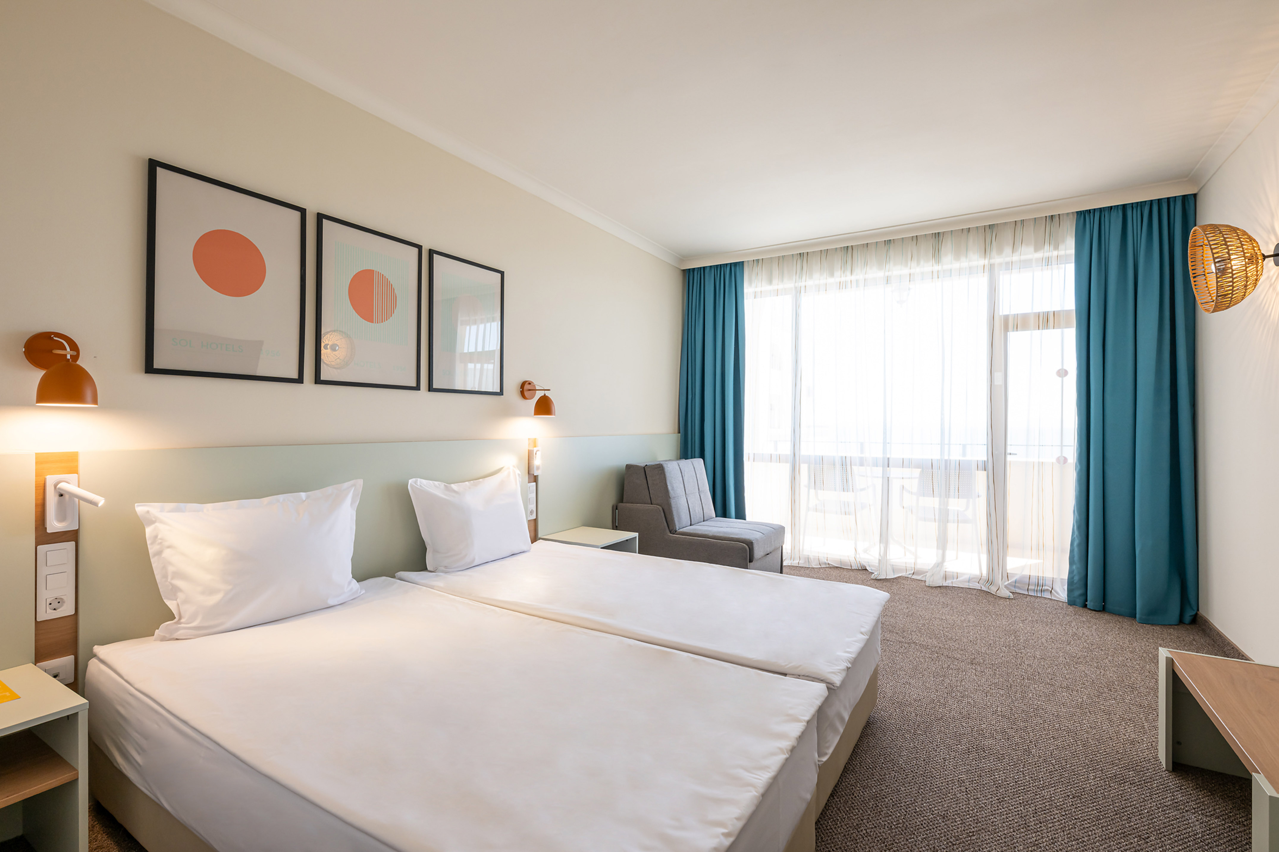 Bright modern hotel room with twin beds, stylish decor, blue curtains, and balcony.