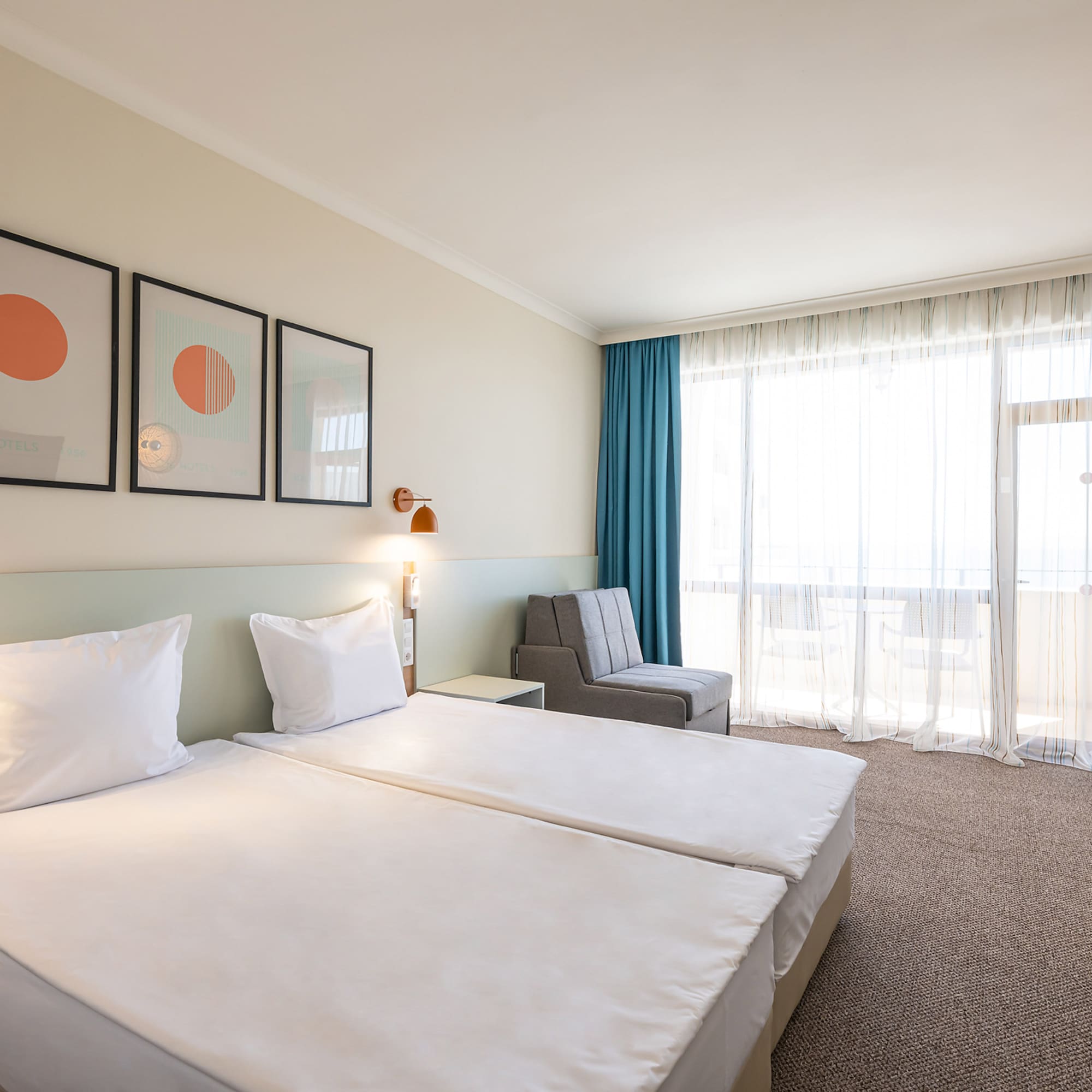 Bright modern hotel room with twin beds, stylish decor, blue curtains, and balcony.