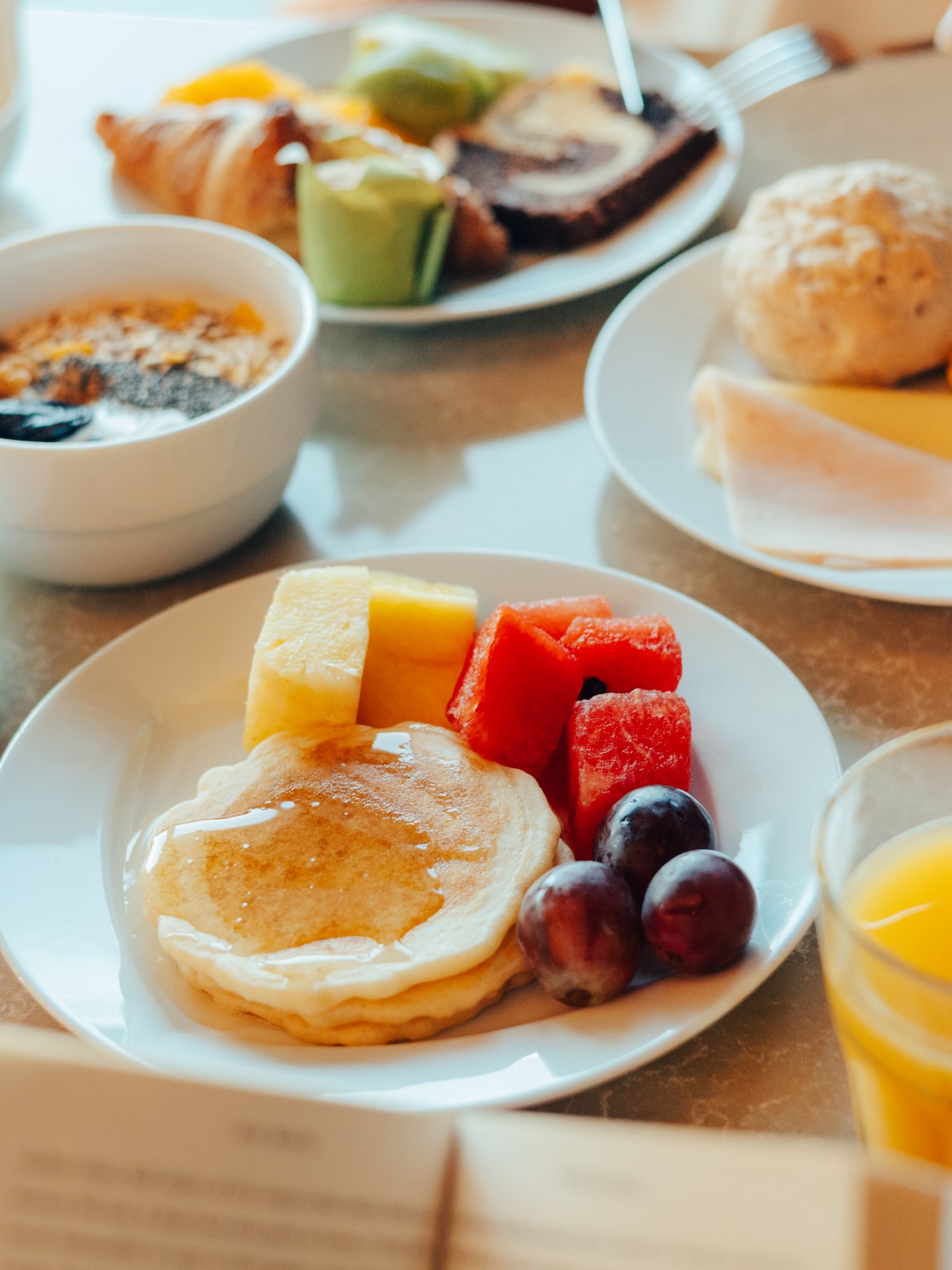 Hotel breakfast buffet: pancakes, fresh fruit, coffee, orange juice, and pastries.