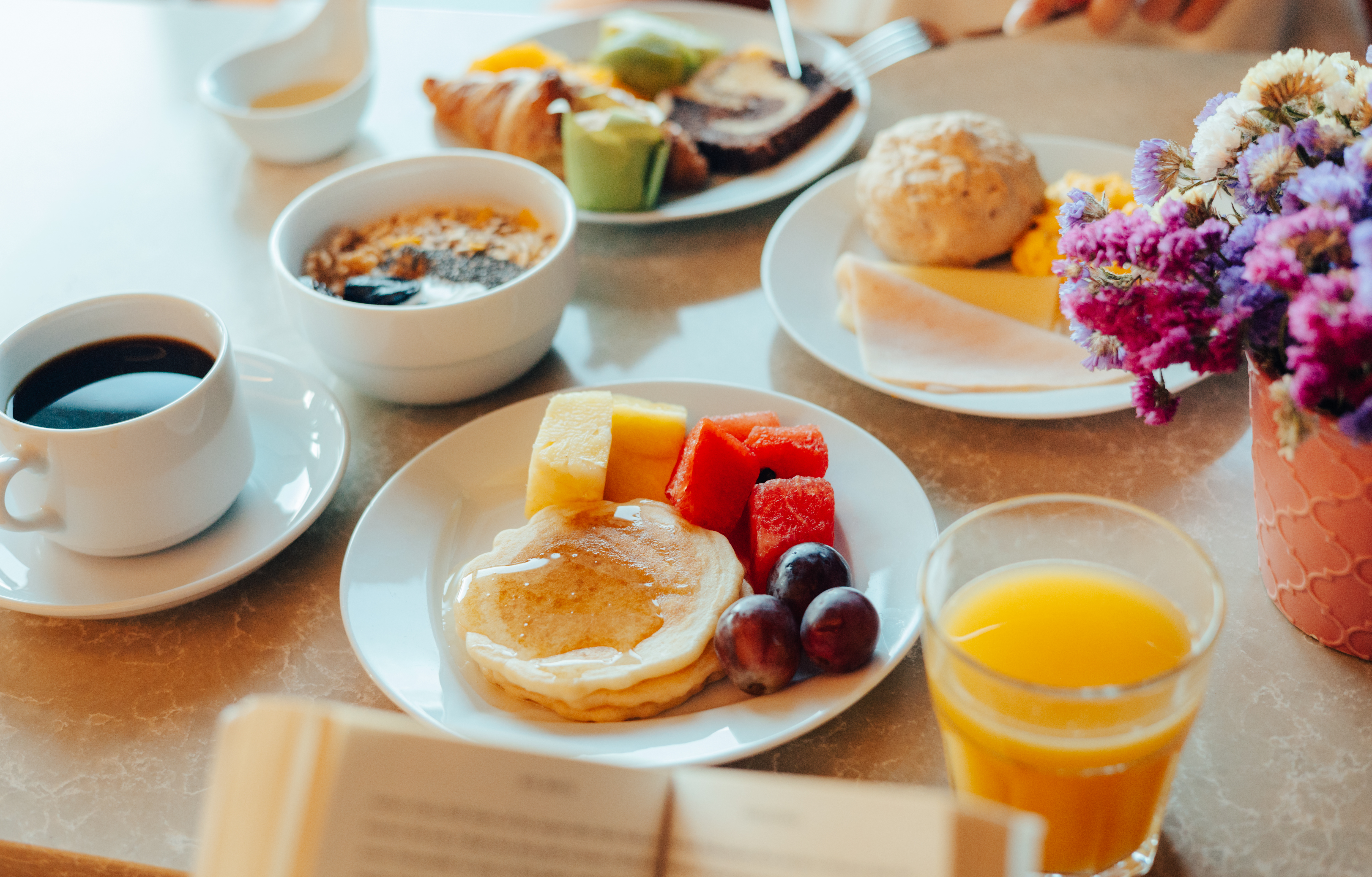 Hotel breakfast buffet: pancakes, fresh fruit, coffee, orange juice, and pastries.